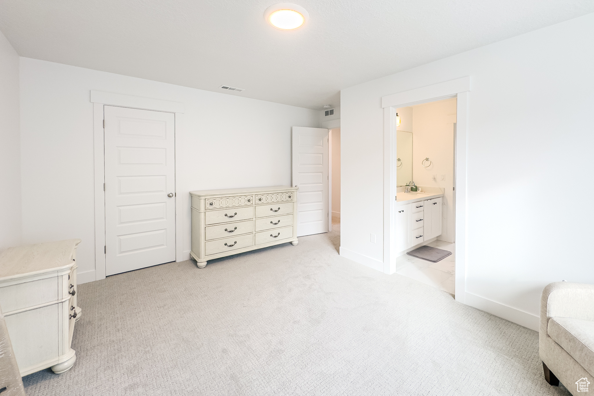 Bedroom with ensuite bathroom, sink, and light carpet