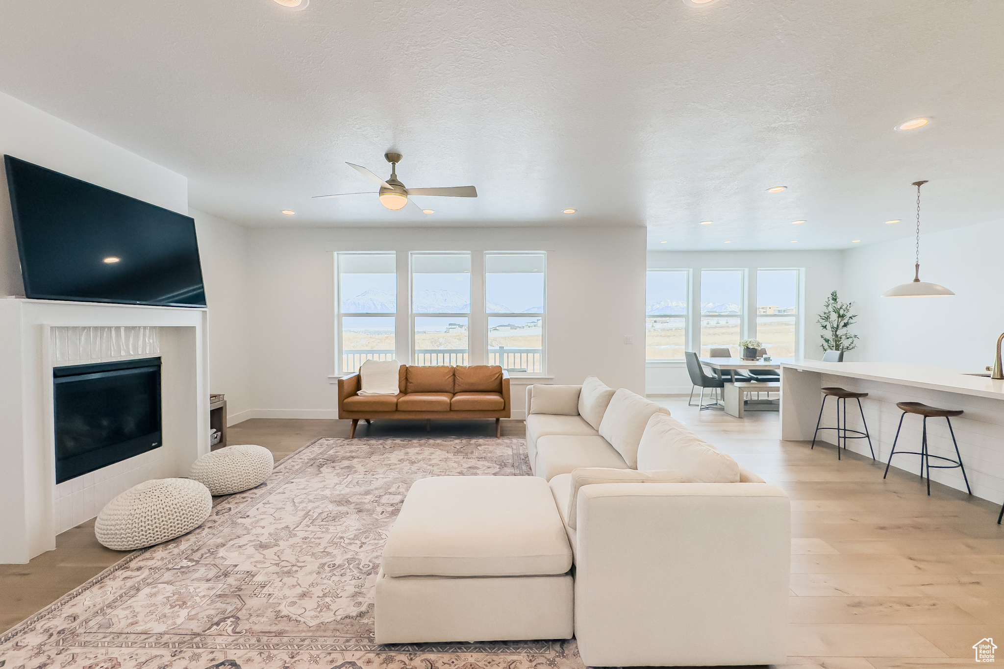 Living room with ceiling fan, a textured ceiling, and light wood-type flooring