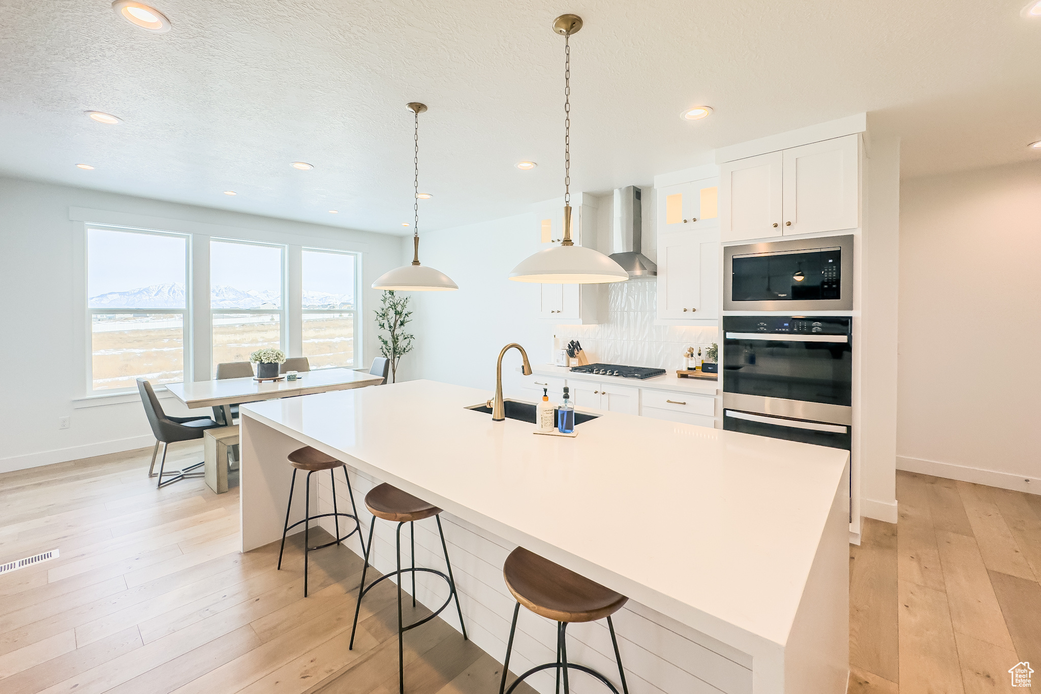 Kitchen with black gas cooktop, built in microwave, an island with sink, sink, and white cabinets