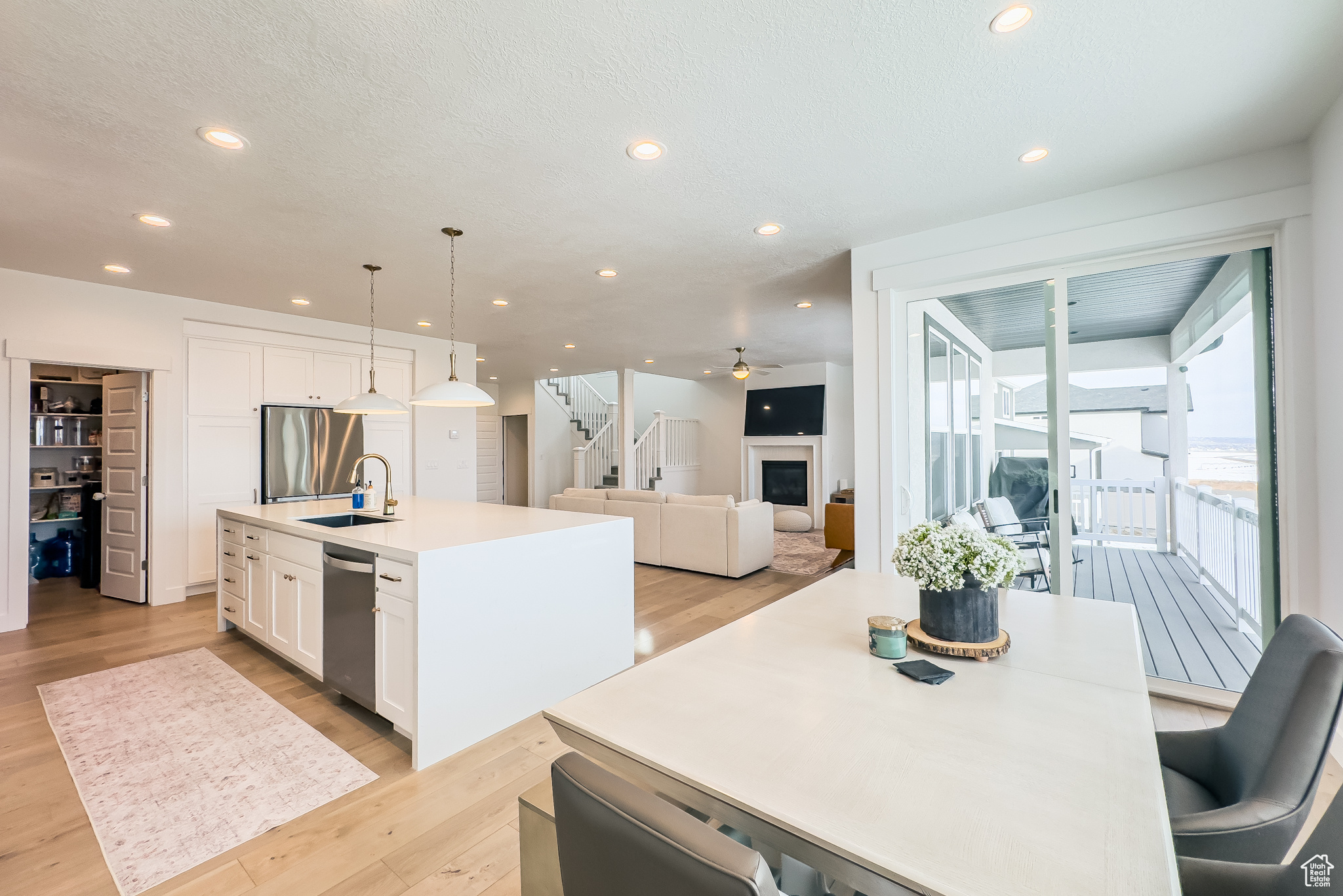 Kitchen featuring white cabinetry, decorative light fixtures, a center island with sink, stainless steel appliances, and light hardwood / wood-style floors