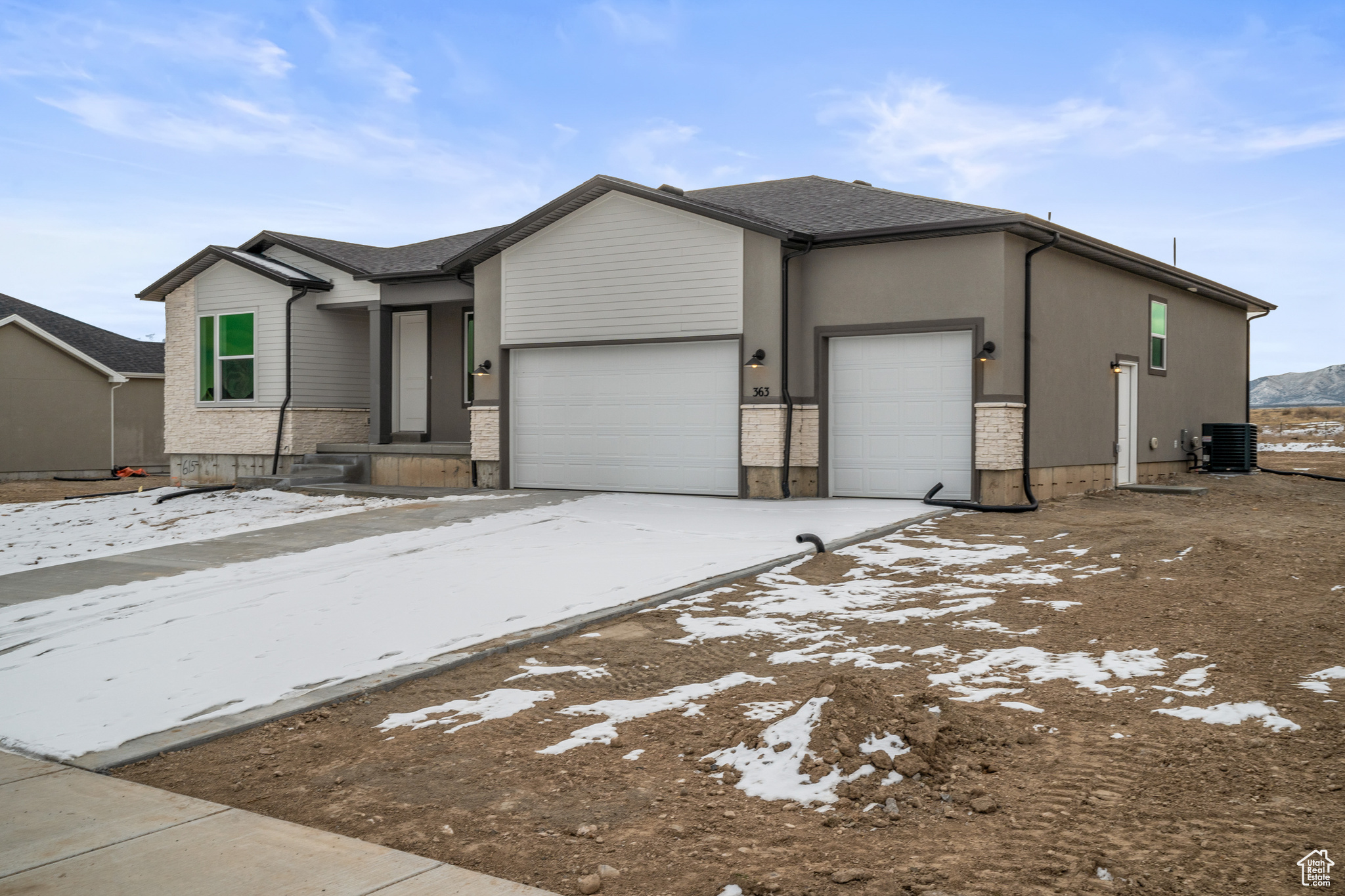 View of front of house featuring a garage and central AC