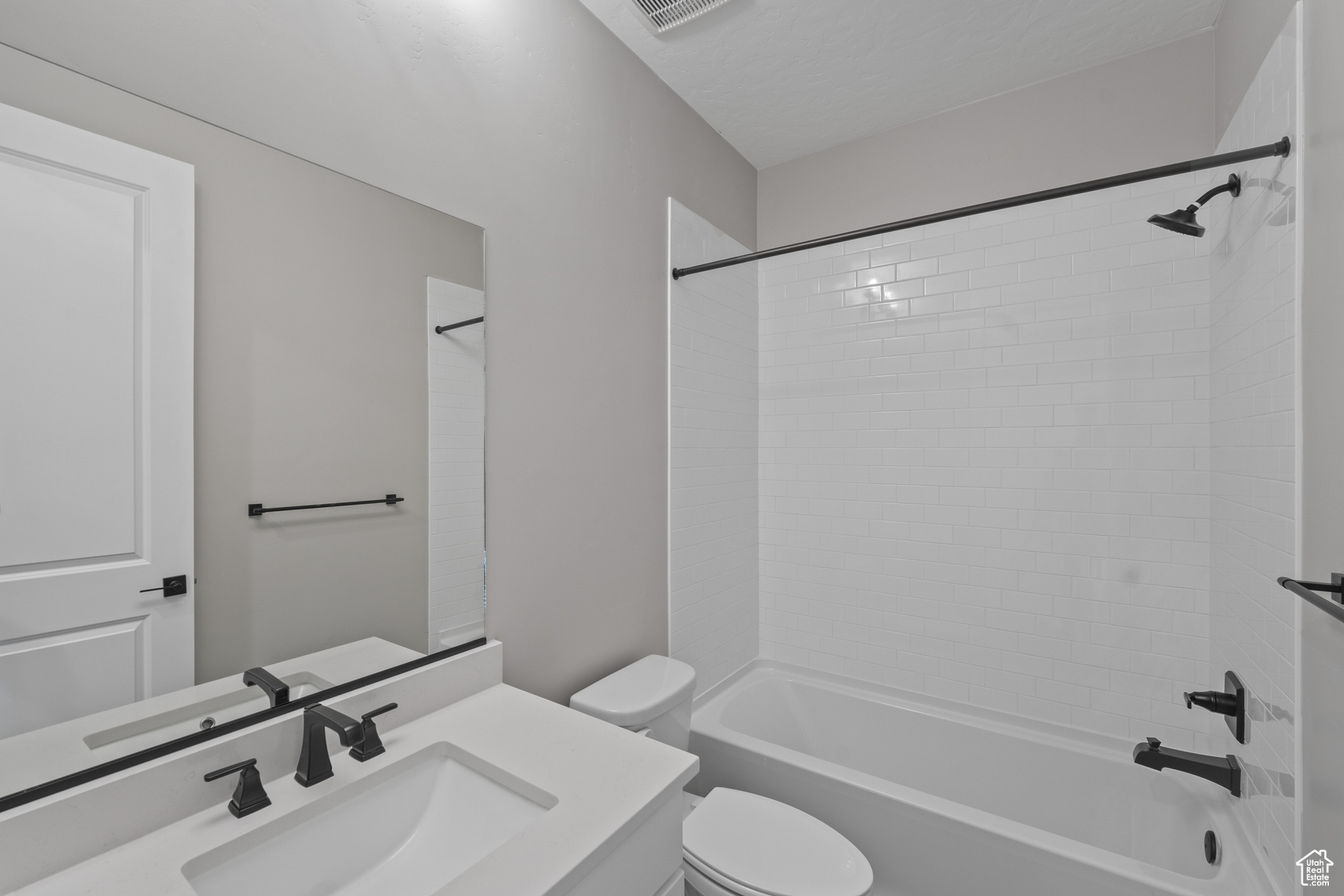 Full bathroom with tiled shower / bath, vanity, and toilet