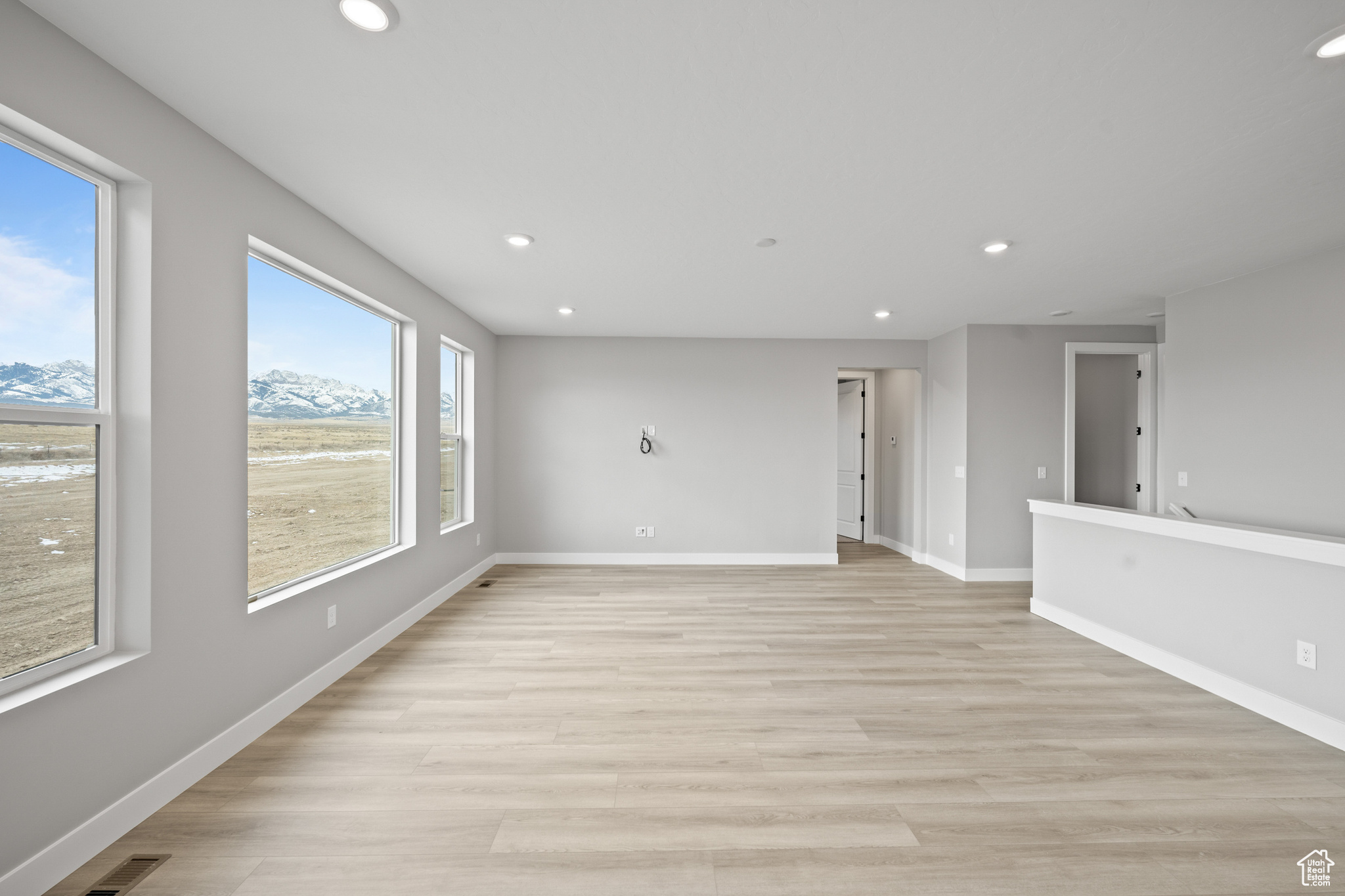 Unfurnished living room with a mountain view and light hardwood / wood-style floors