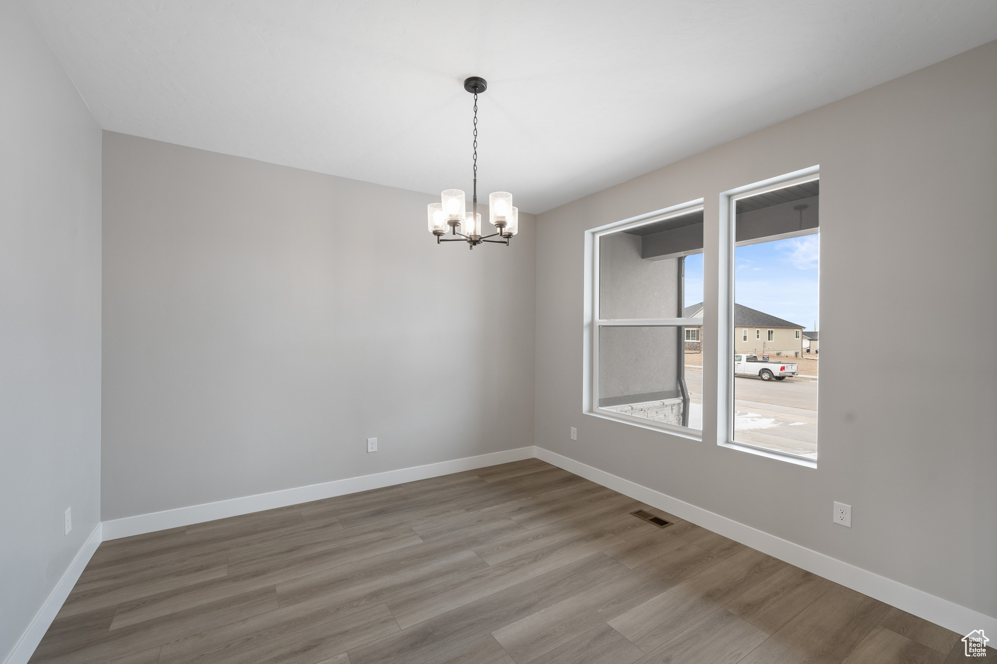 Unfurnished room with an inviting chandelier and hardwood / wood-style floors