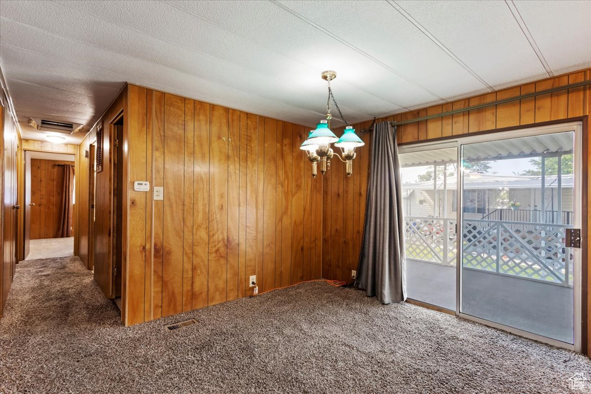 Unfurnished dining area featuring carpet floors, a textured ceiling, and wooden walls