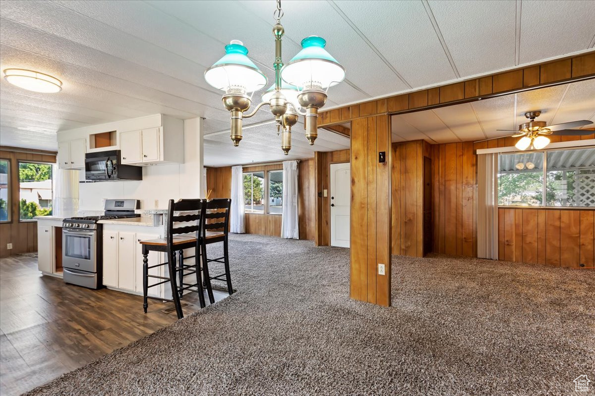 Kitchen with white cabinetry, gas range, plenty of natural light, and wood walls