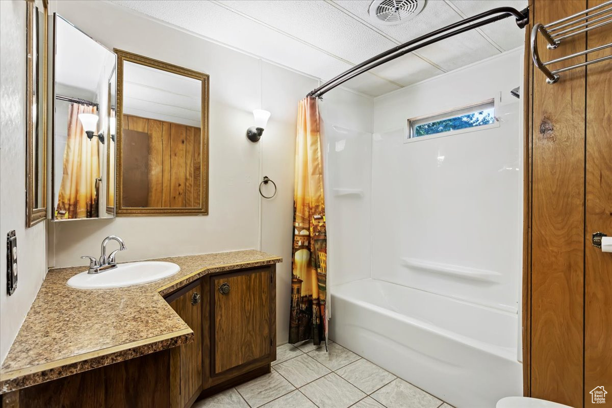 Bathroom with vanity, tile patterned floors, and shower / bath combination with curtain