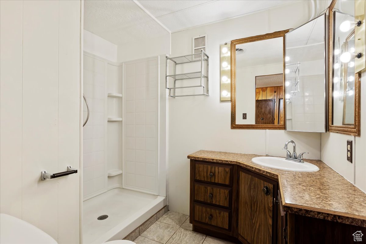 Bathroom featuring vanity, toilet, tile patterned flooring, and a shower