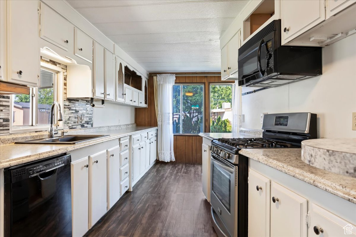 Kitchen with dark hardwood / wood-style floors, sink, backsplash, white cabinets, and black appliances