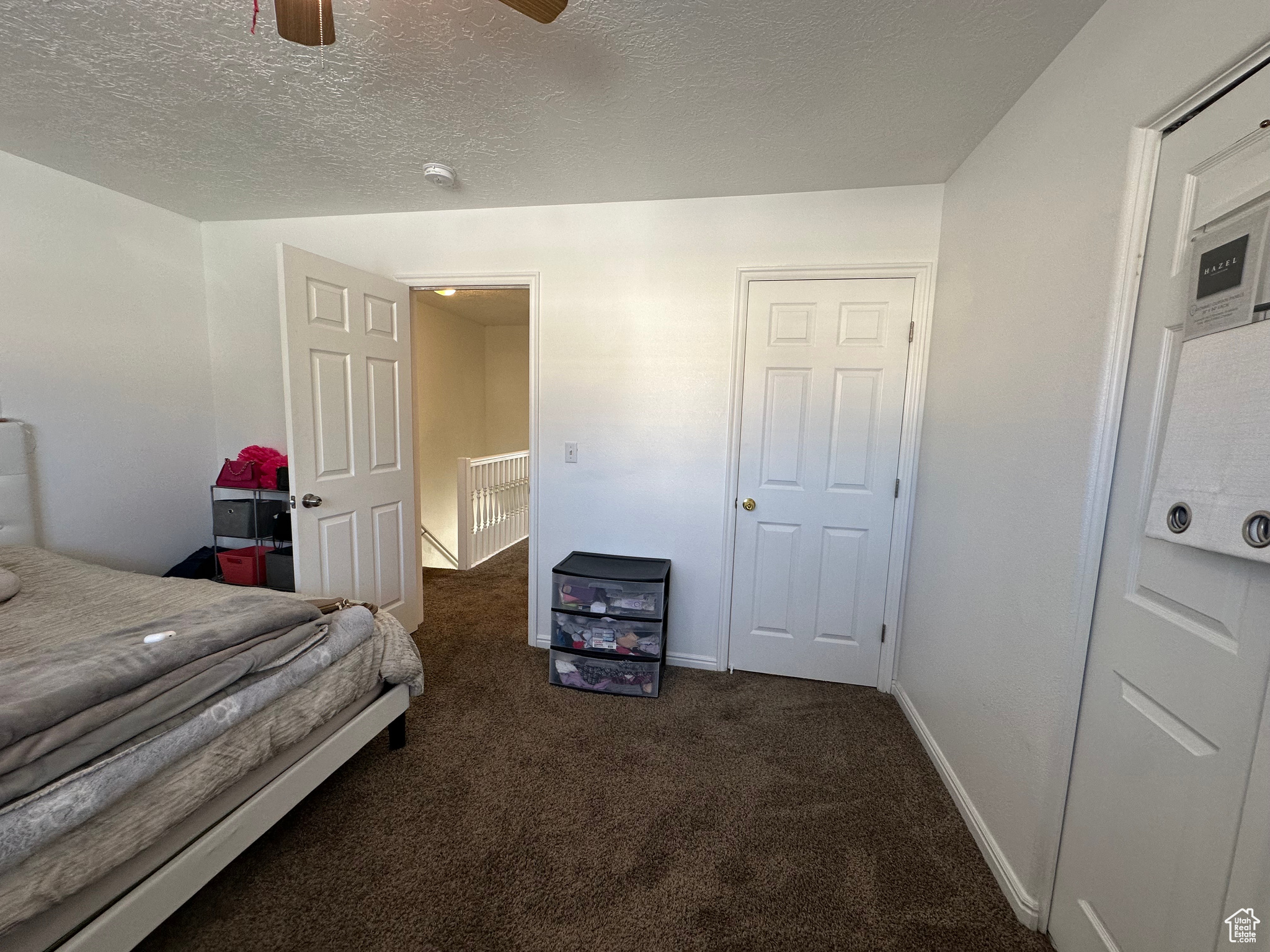 Carpeted bedroom featuring ceiling fan and a textured ceiling