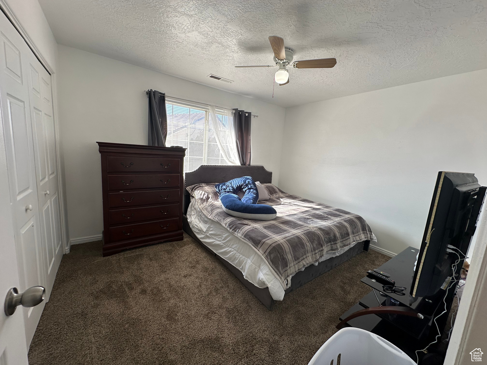 Bedroom featuring dark carpet, a textured ceiling, a closet, and ceiling fan