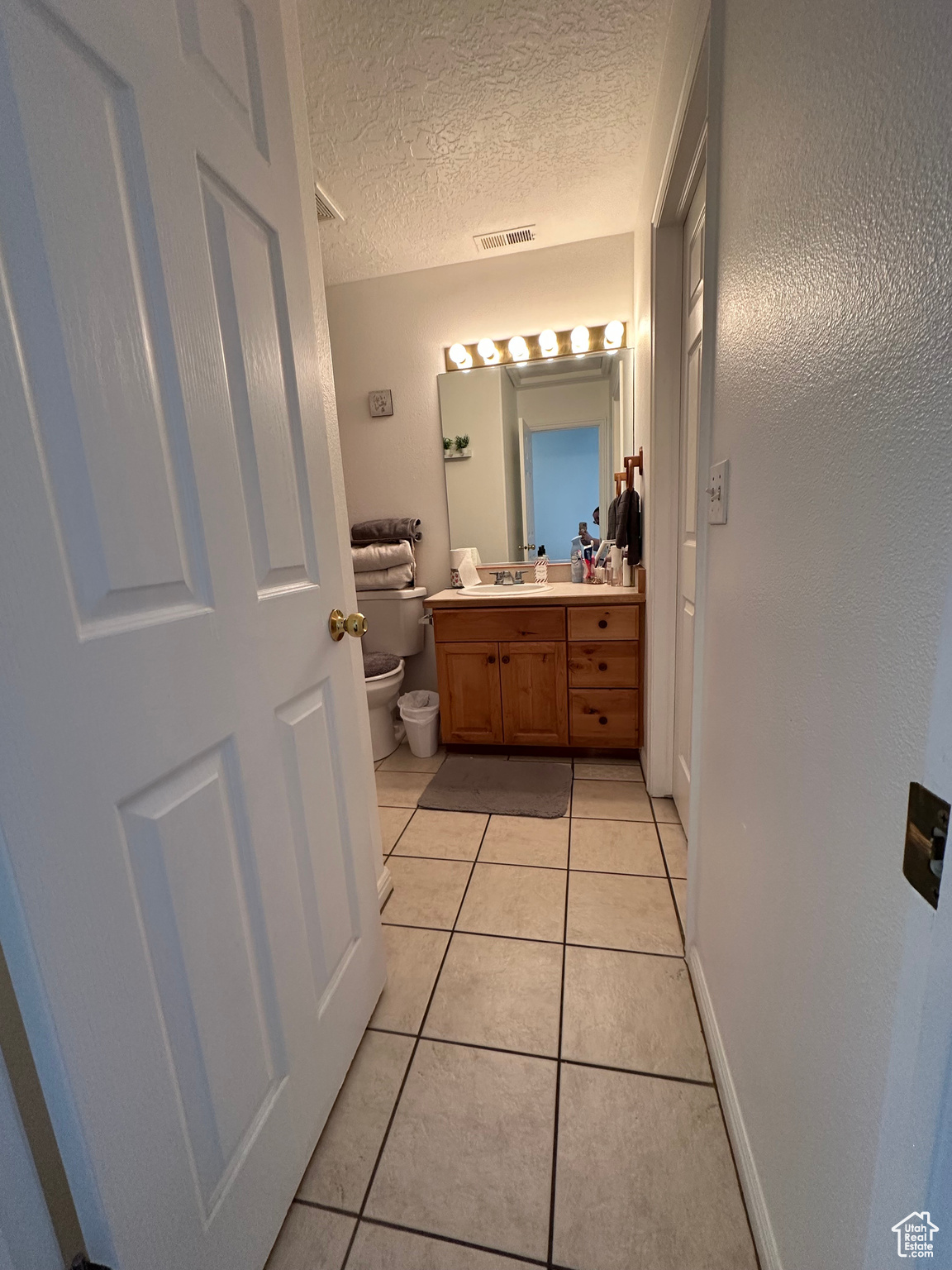 Bathroom featuring vanity, toilet, tile patterned flooring, and a textured ceiling