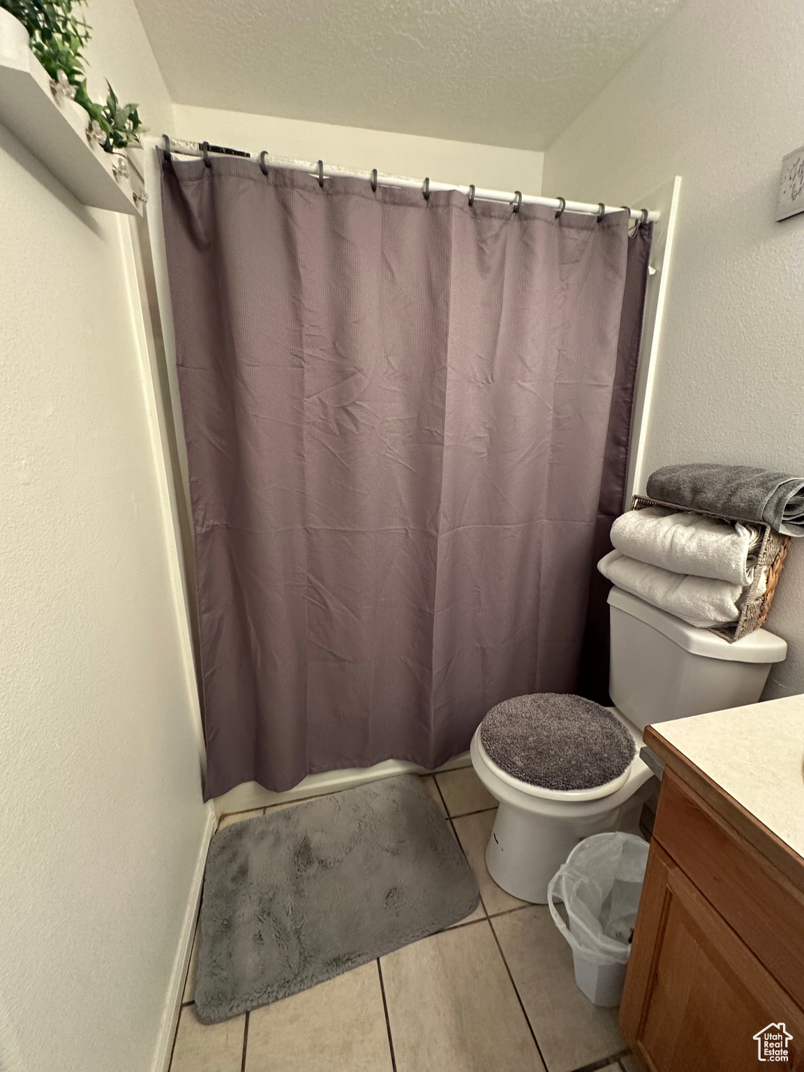 Bathroom featuring tile patterned flooring, vanity, a textured ceiling, and toilet