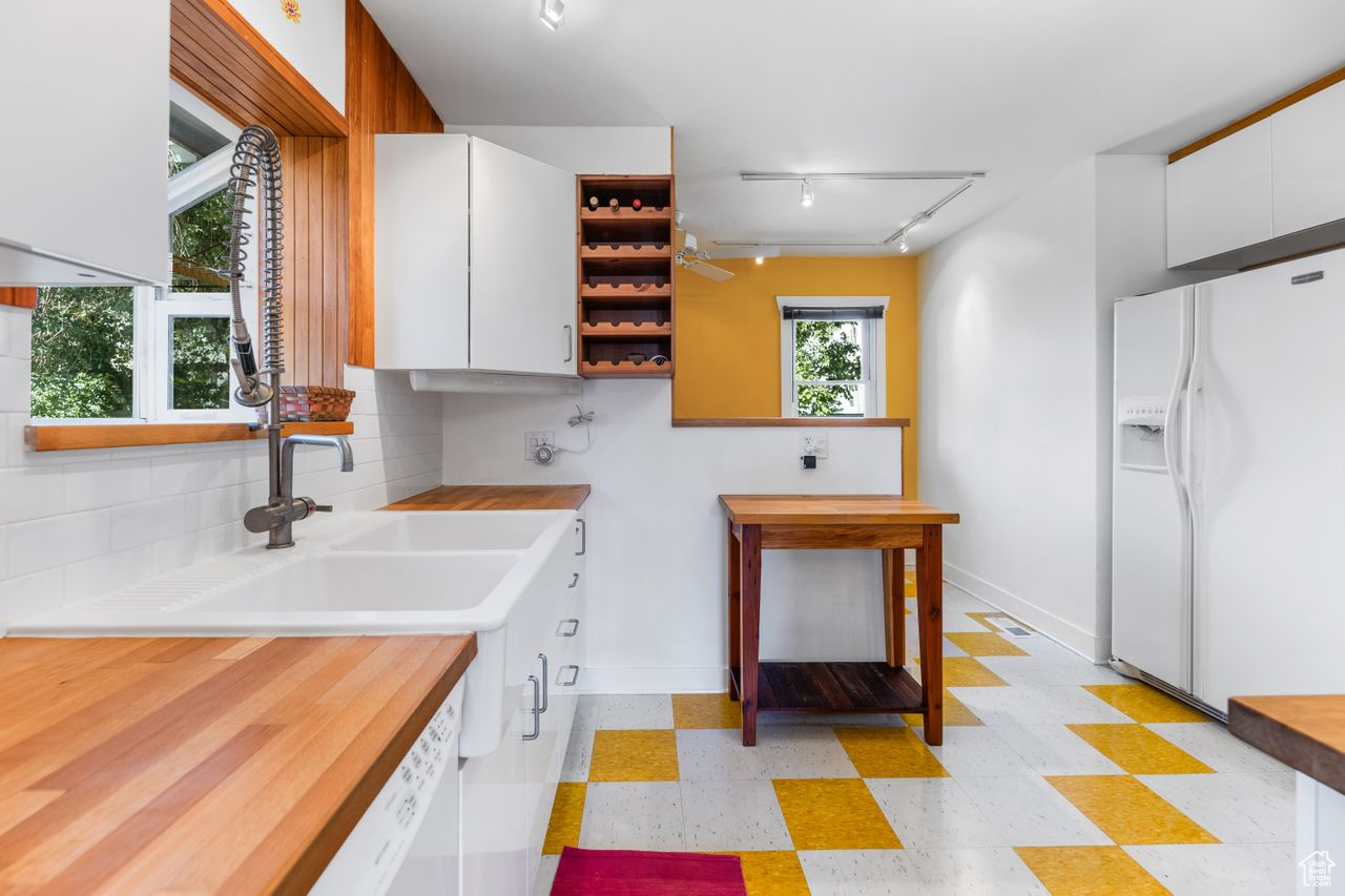 Kitchen with white cabinetry, backsplash, and white appliances