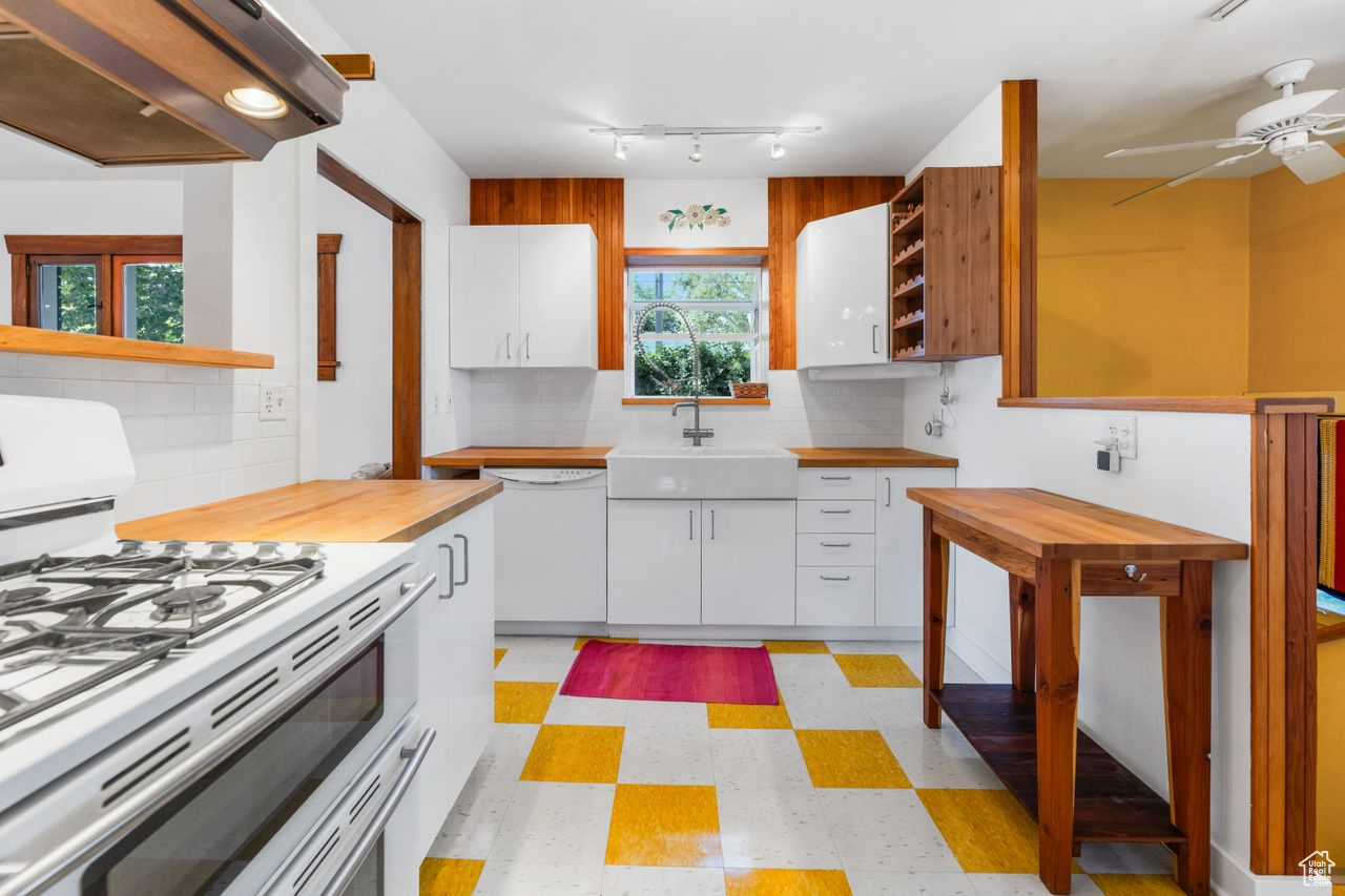 Kitchen with white appliances, sink, exhaust hood, and white cabinets