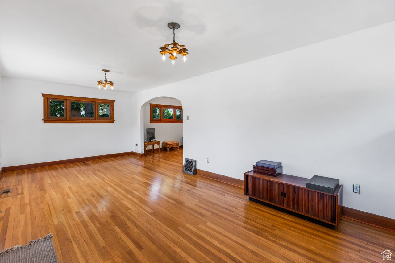 Spare room with a notable chandelier and hardwood / wood-style flooring