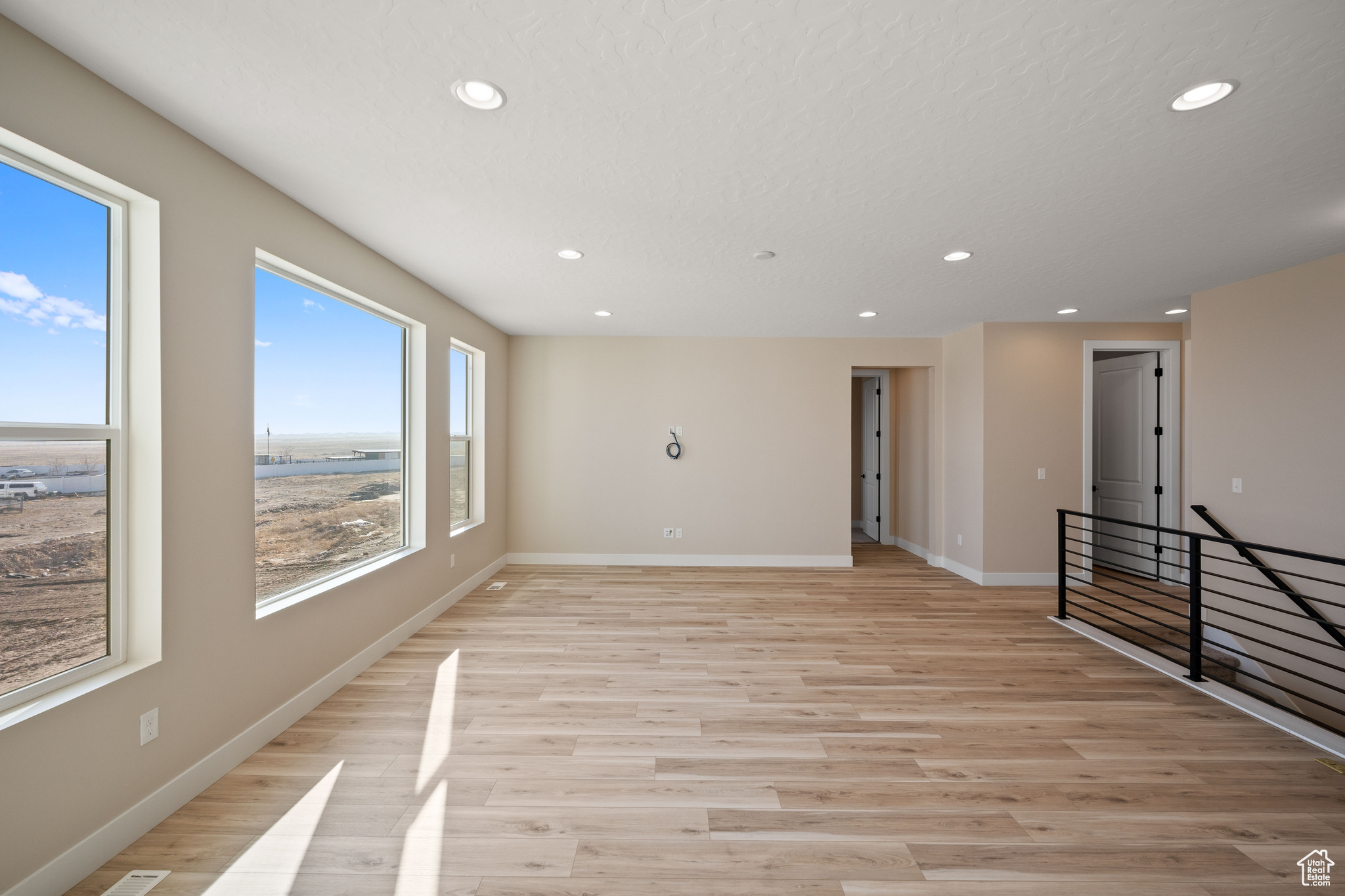 Empty room with a textured ceiling and light wood-type flooring