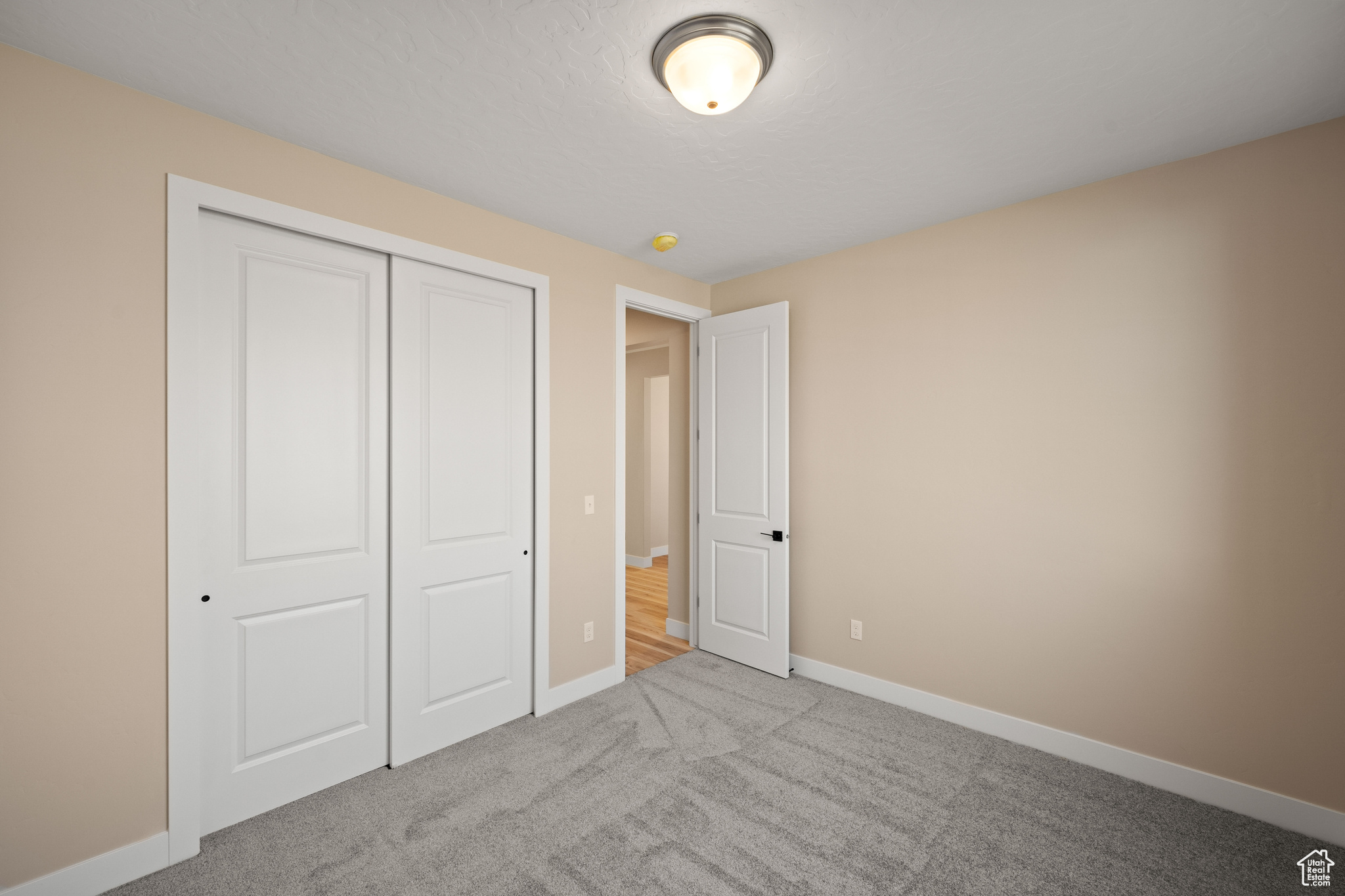 Unfurnished bedroom featuring light carpet and a closet