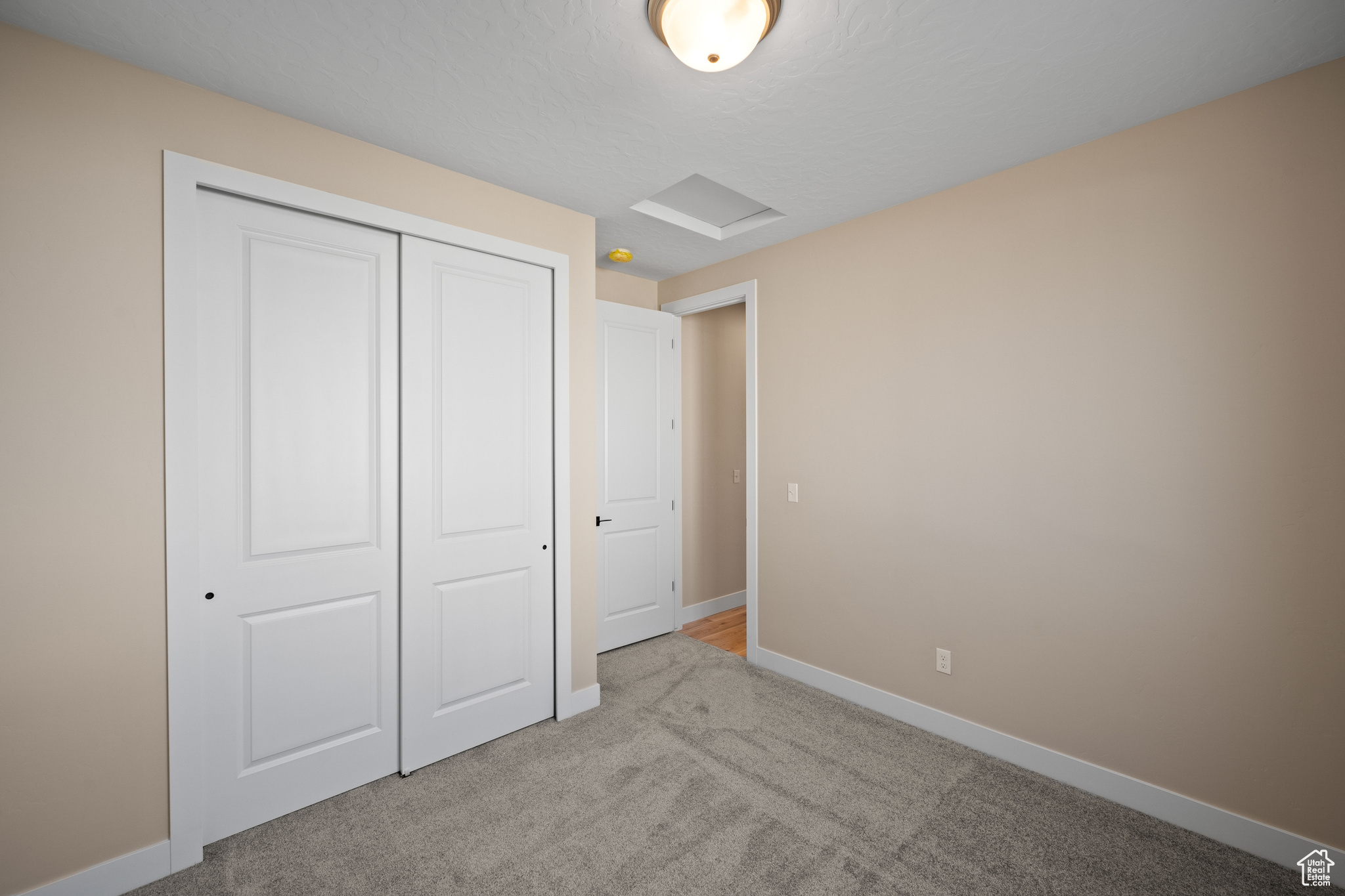 Unfurnished bedroom with light carpet and a closet