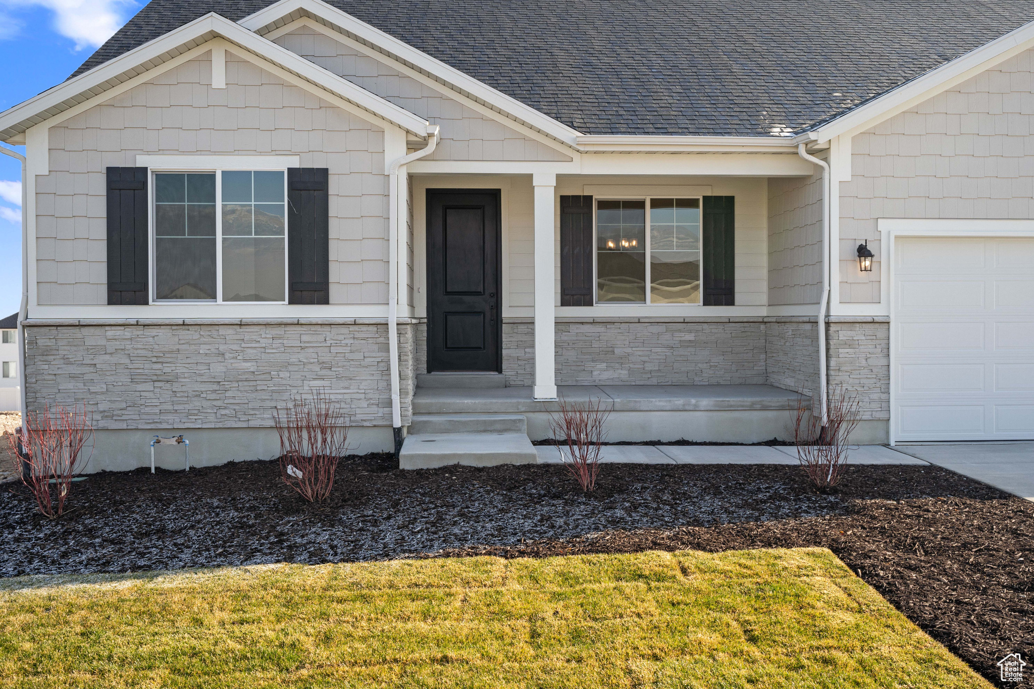 View of exterior entry with a garage, a lawn, and covered porch