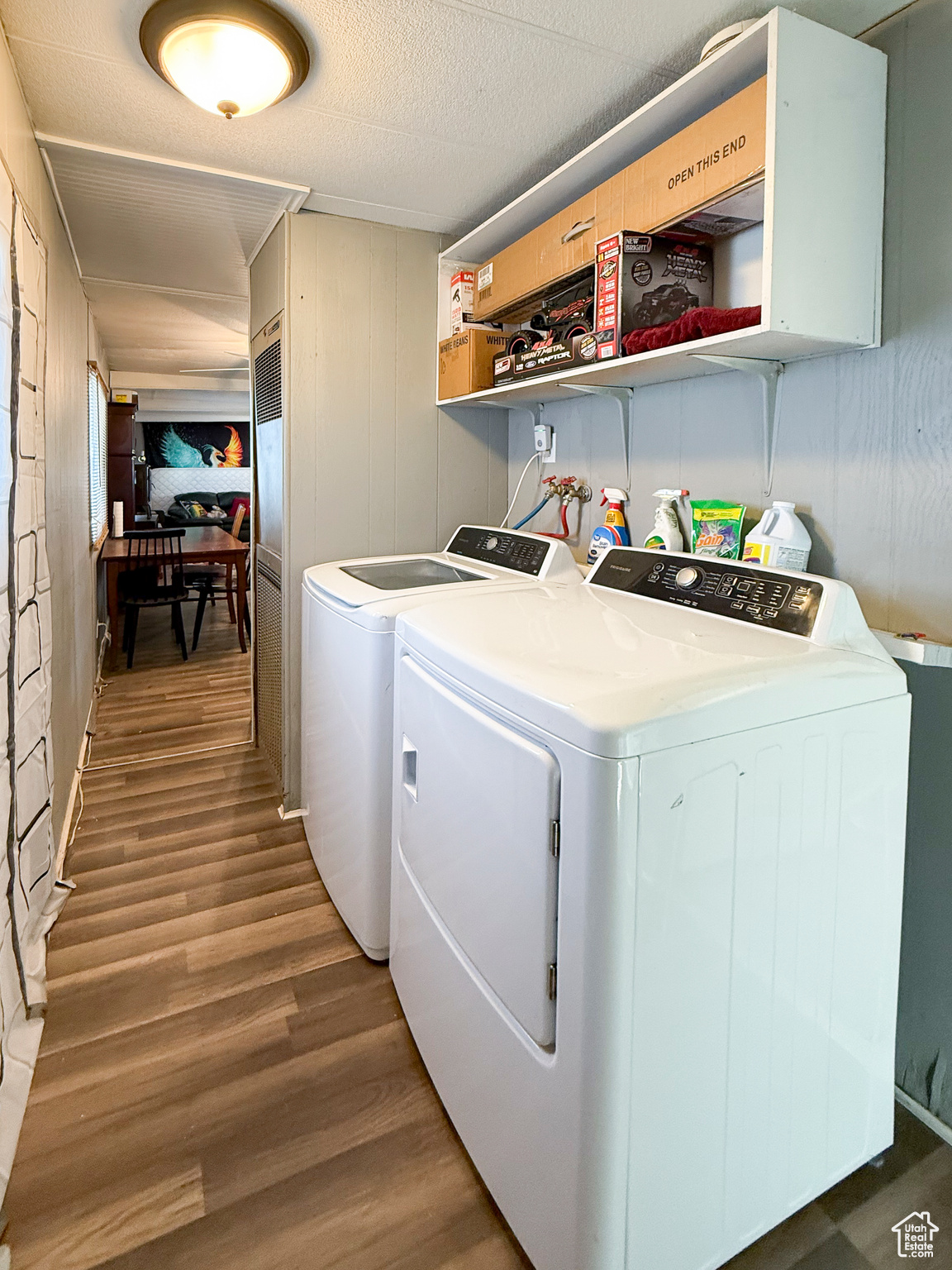 Washroom with dark wood-type flooring, washing machine and clothes dryer, and a textured ceiling