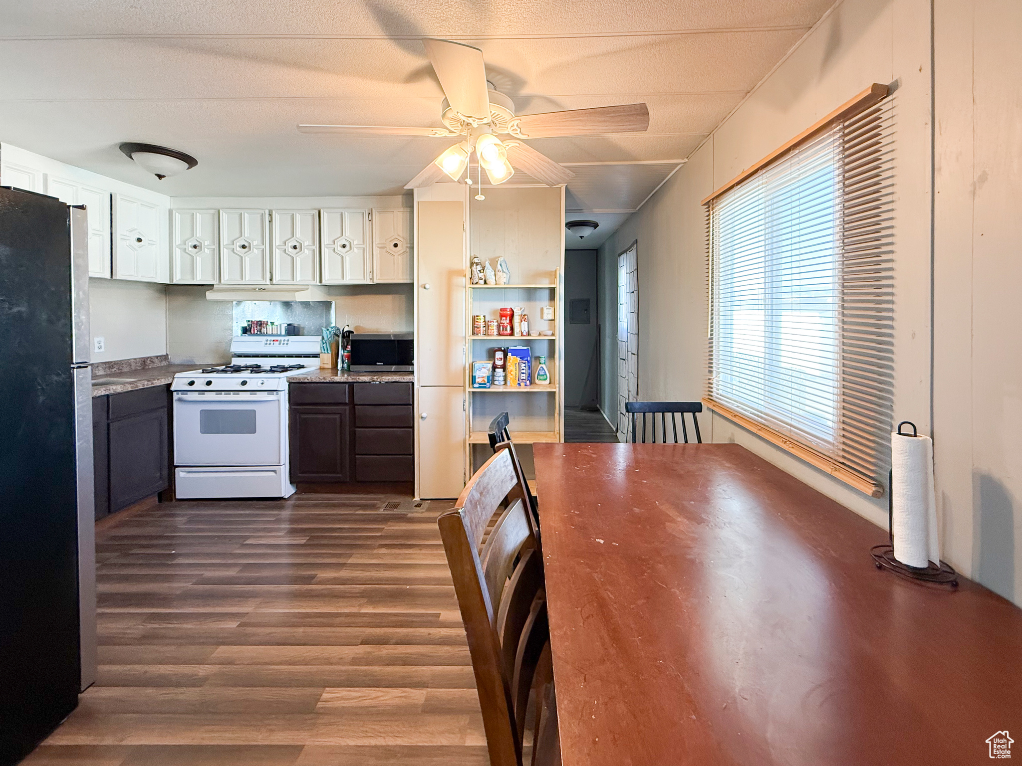 Kitchen with white cabinetry, dark wood-type flooring, ceiling fan, and appliances with stainless steel finishes