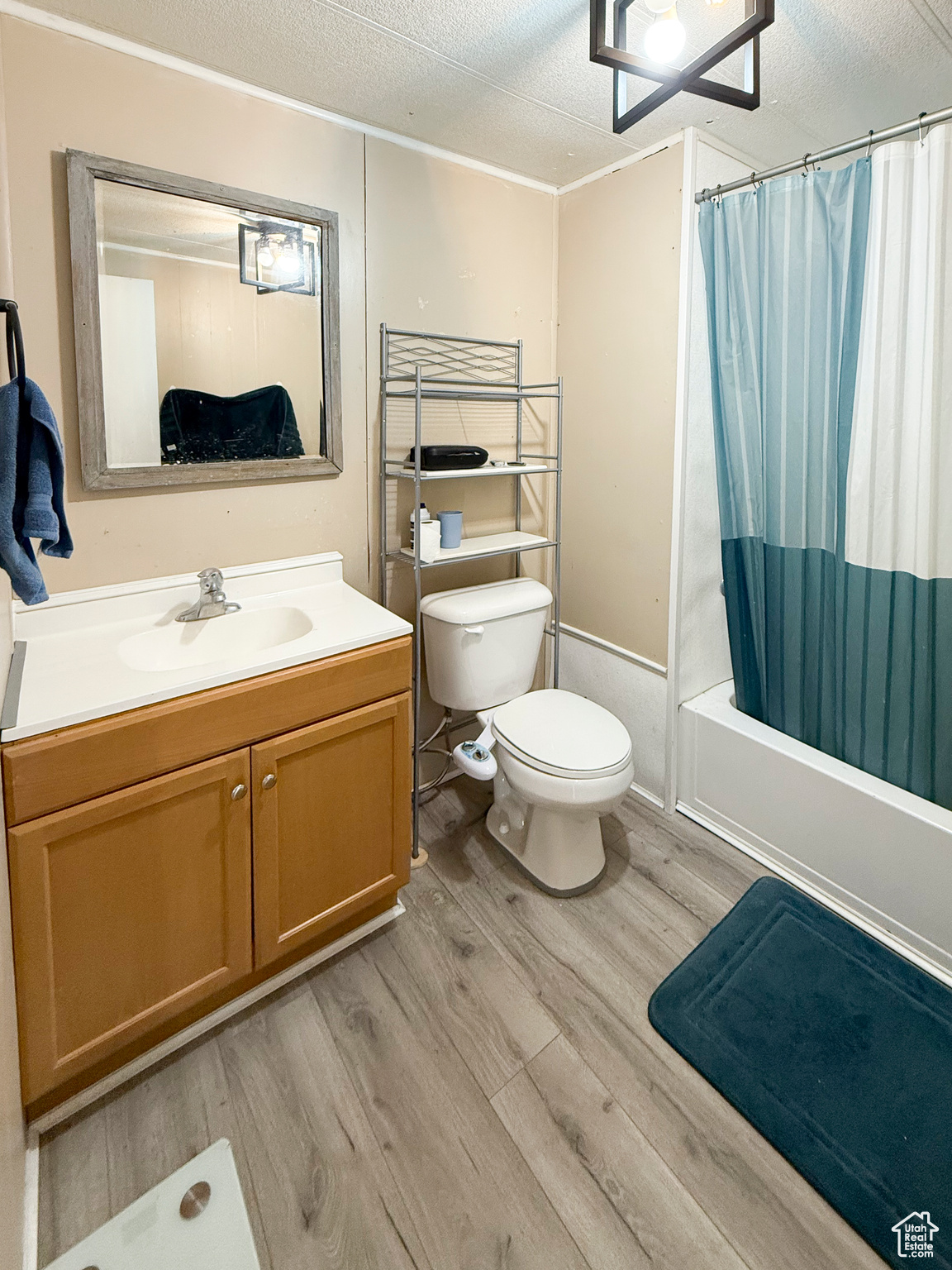 Full bathroom featuring vanity, hardwood / wood-style floors, shower / bath combo, and a textured ceiling