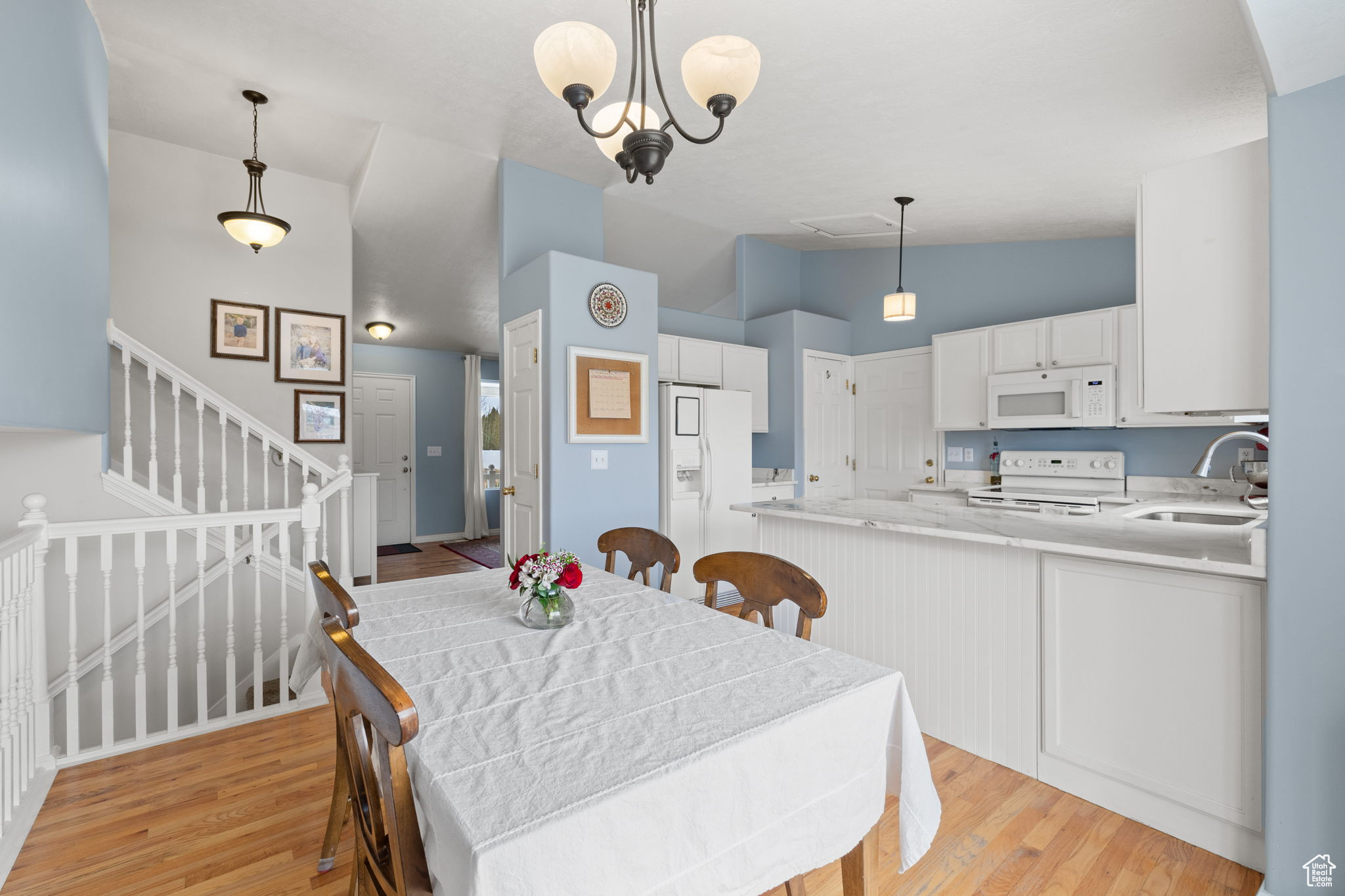 Dining space with lofted ceiling, sink, a notable chandelier, and light hardwood / wood-style flooring