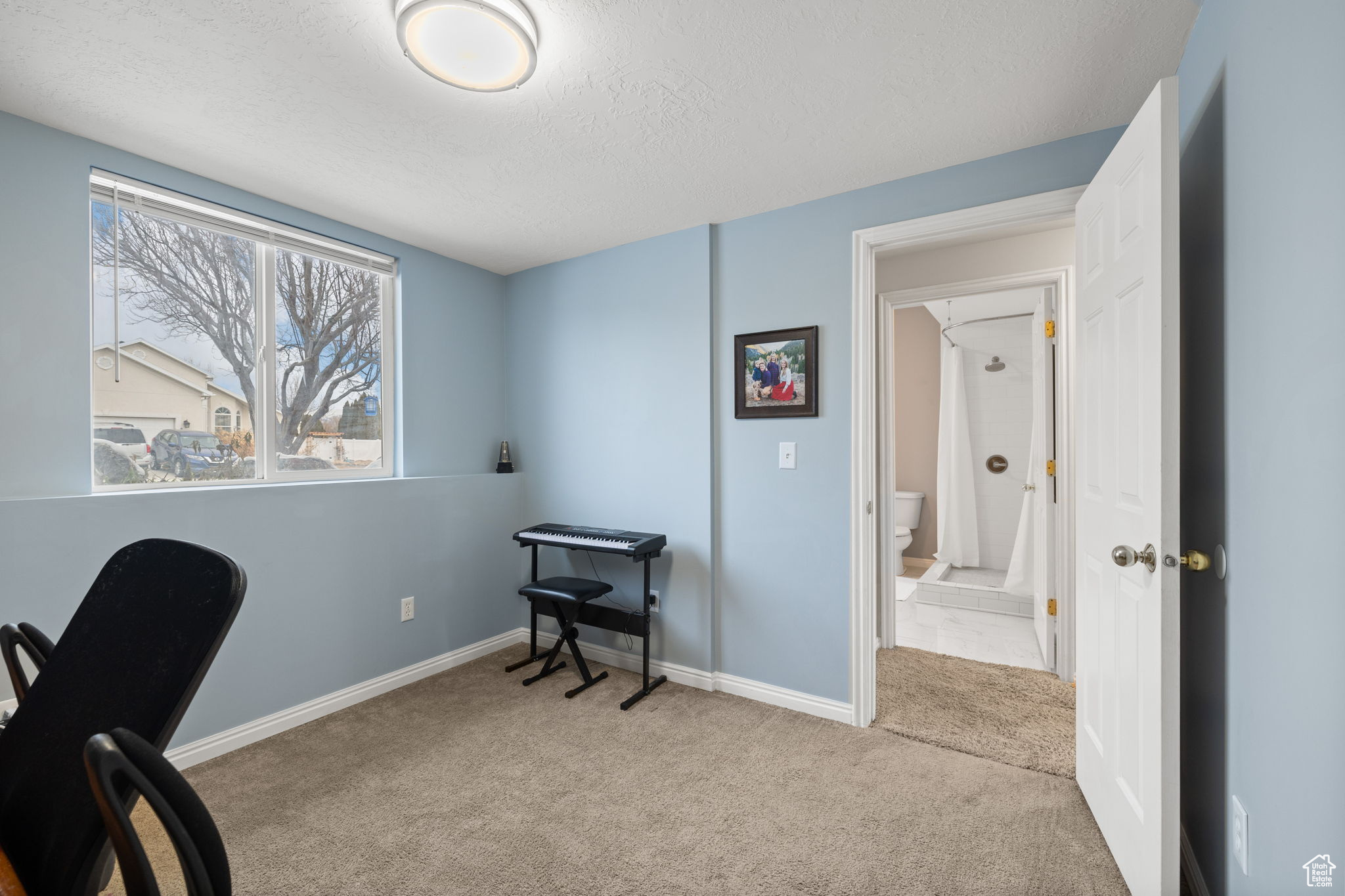 Carpeted home office with a textured ceiling