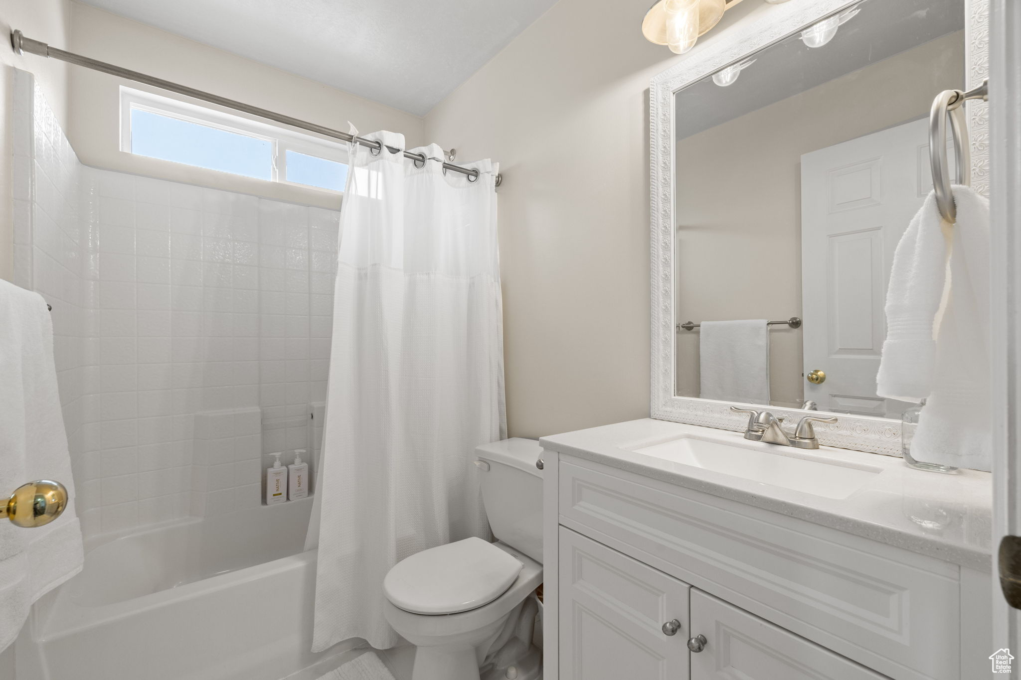 Full bathroom featuring toilet, vanity, and shower / bathtub combination with curtain