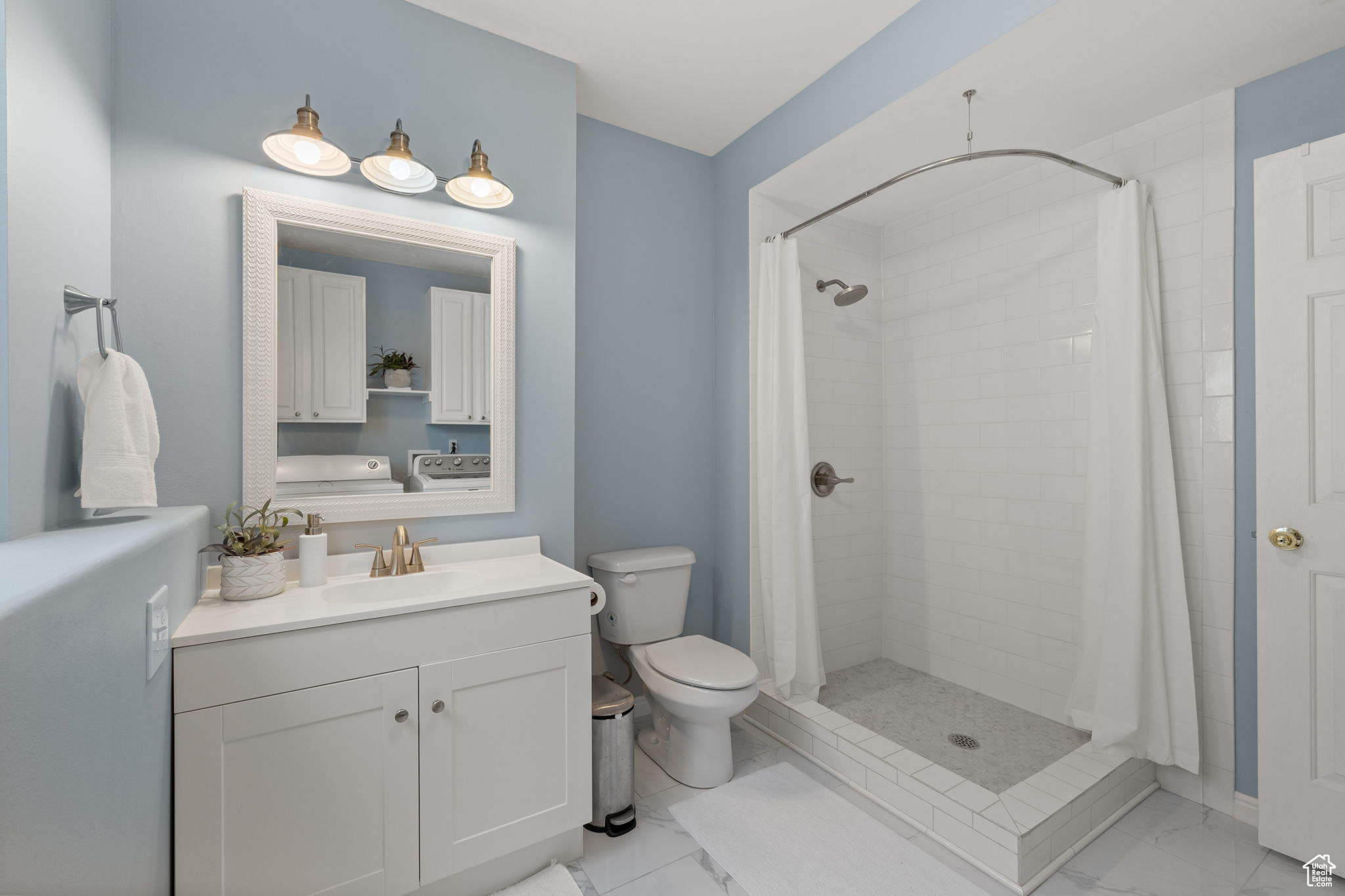 Bathroom featuring vanity, independent washer and dryer, toilet, and a shower with shower curtain