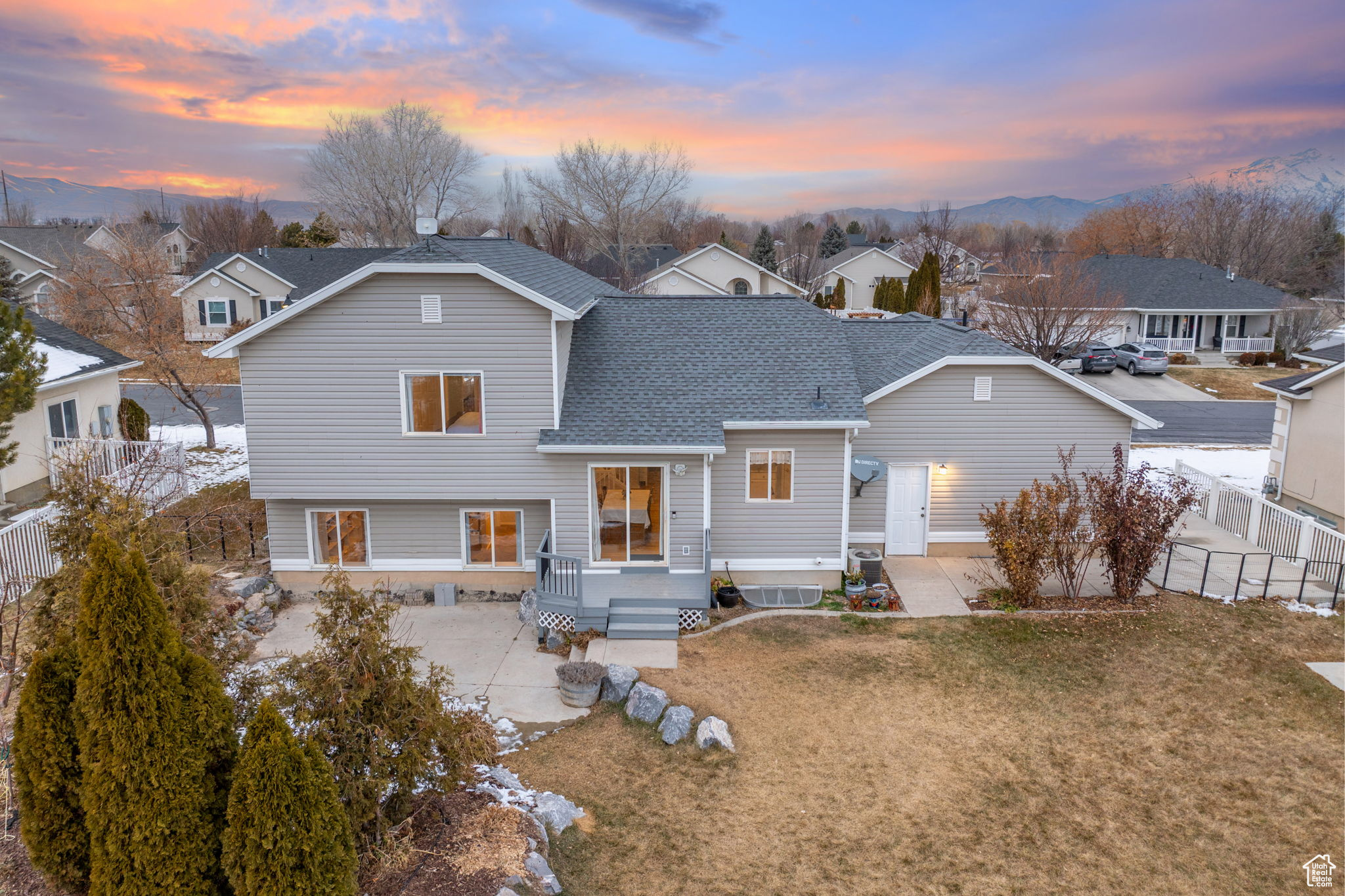 Back house at dusk featuring a mountain view, a lawn, and a patio