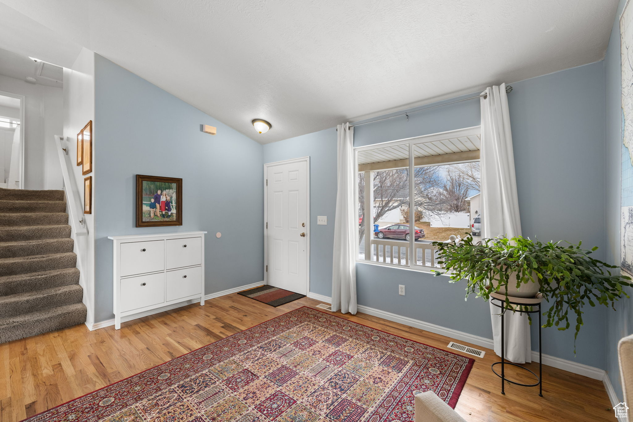 Entrance foyer with hardwood / wood-style flooring and vaulted ceiling