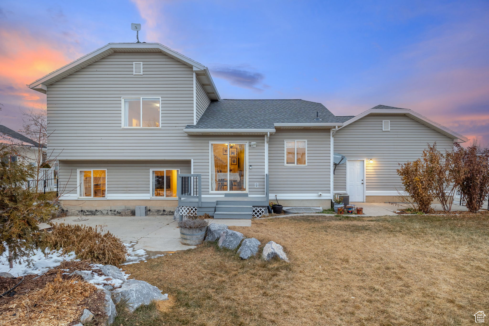 Back house at dusk with a yard and a patio