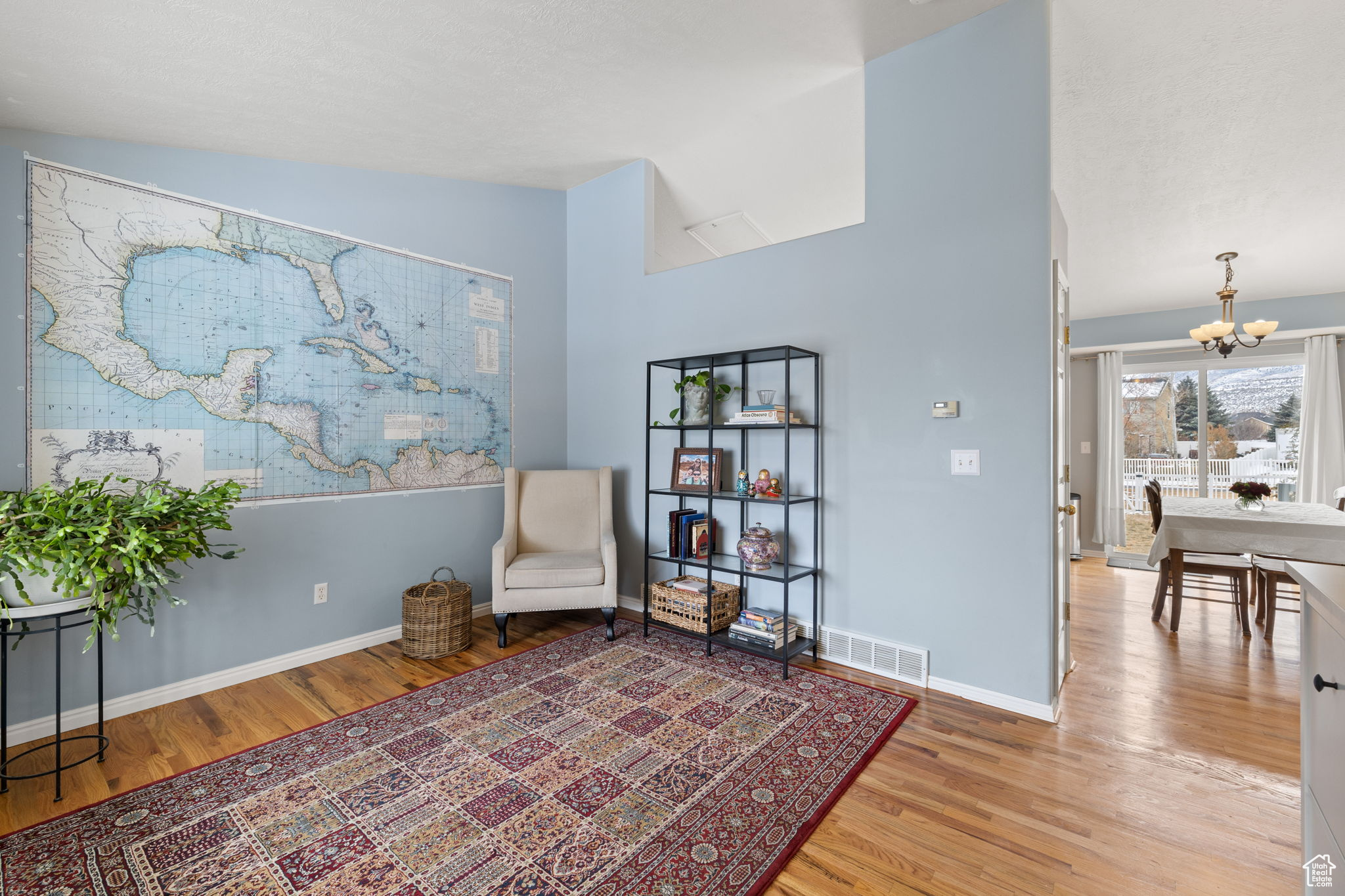 Living area with lofted ceiling, light hardwood / wood-style floors, and a chandelier