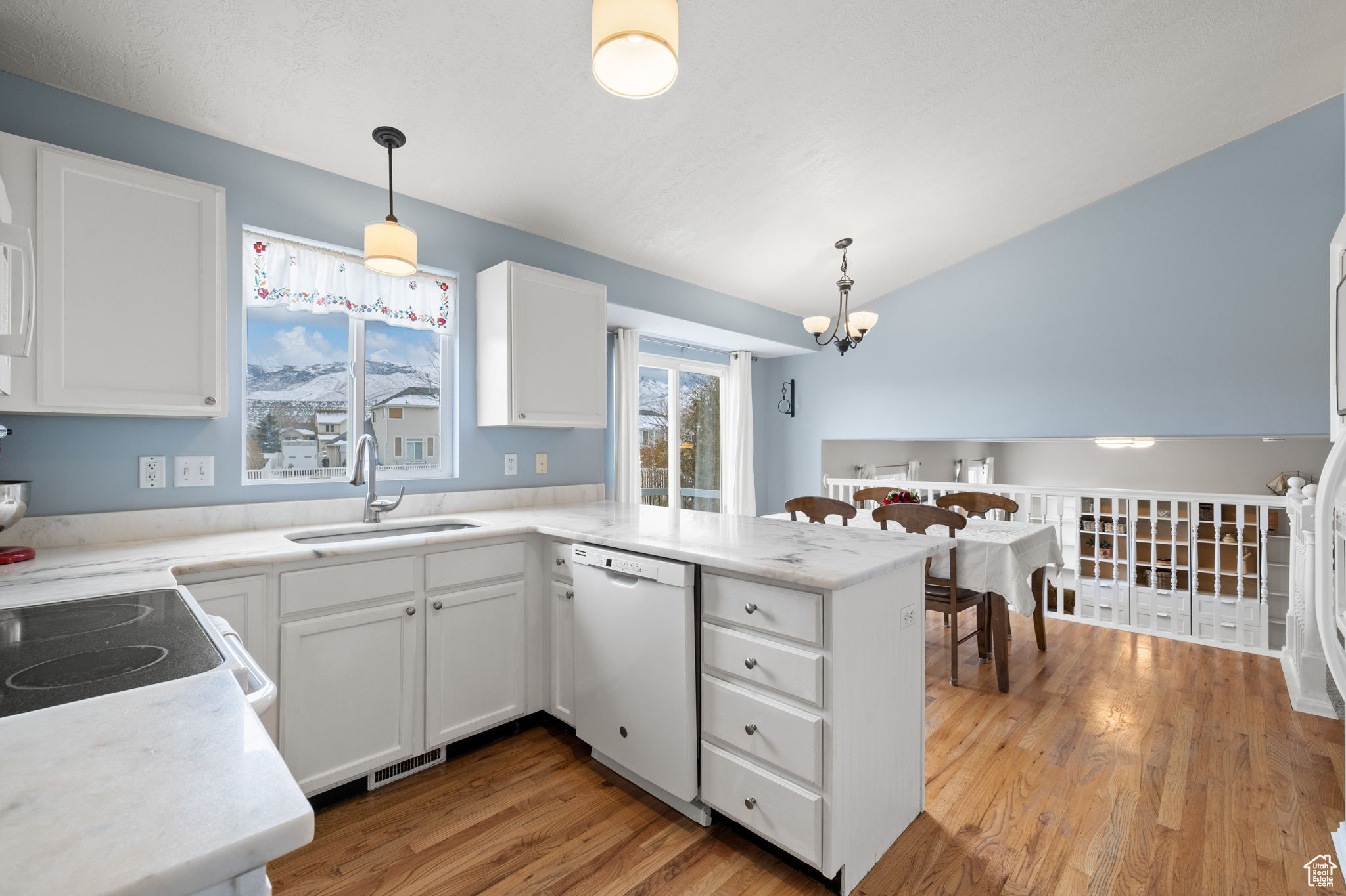 Kitchen featuring pendant lighting, sink, white dishwasher, white cabinets, and kitchen peninsula