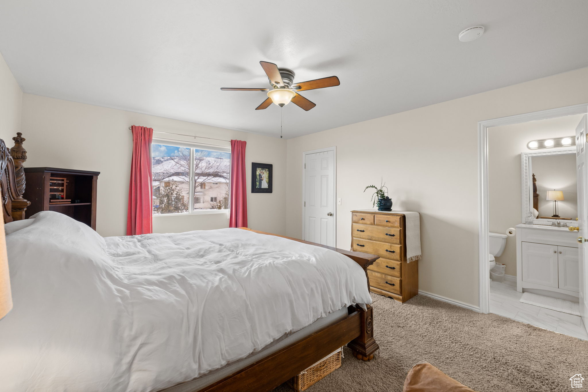 Bedroom with ceiling fan, ensuite bathroom, and light carpet