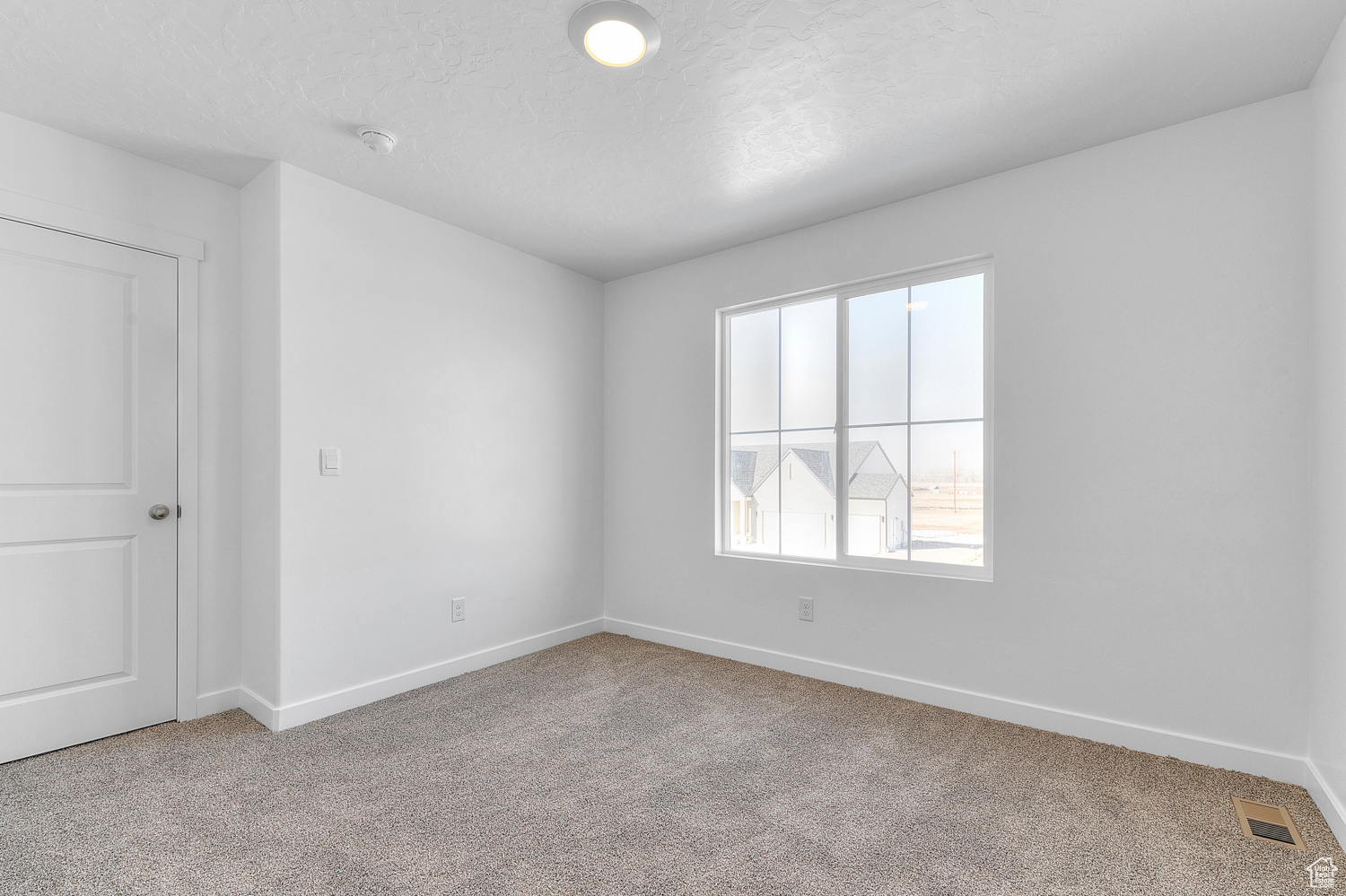 Empty room featuring light carpet and a textured ceiling