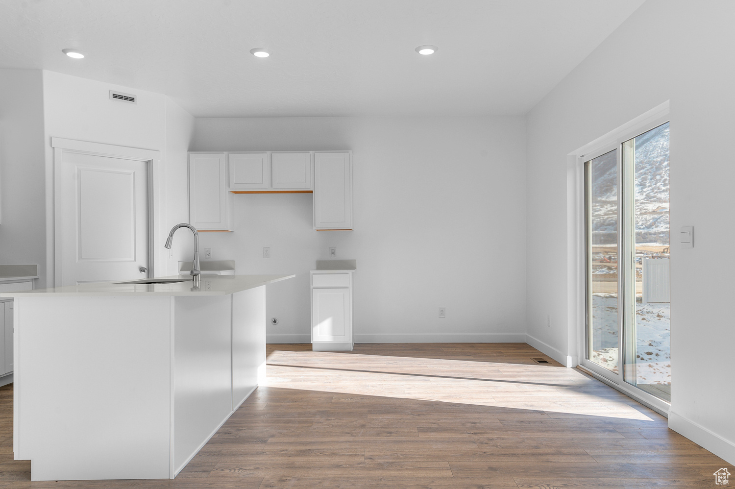 Kitchen featuring white cabinetry, sink, a center island with sink, and light wood-type flooring