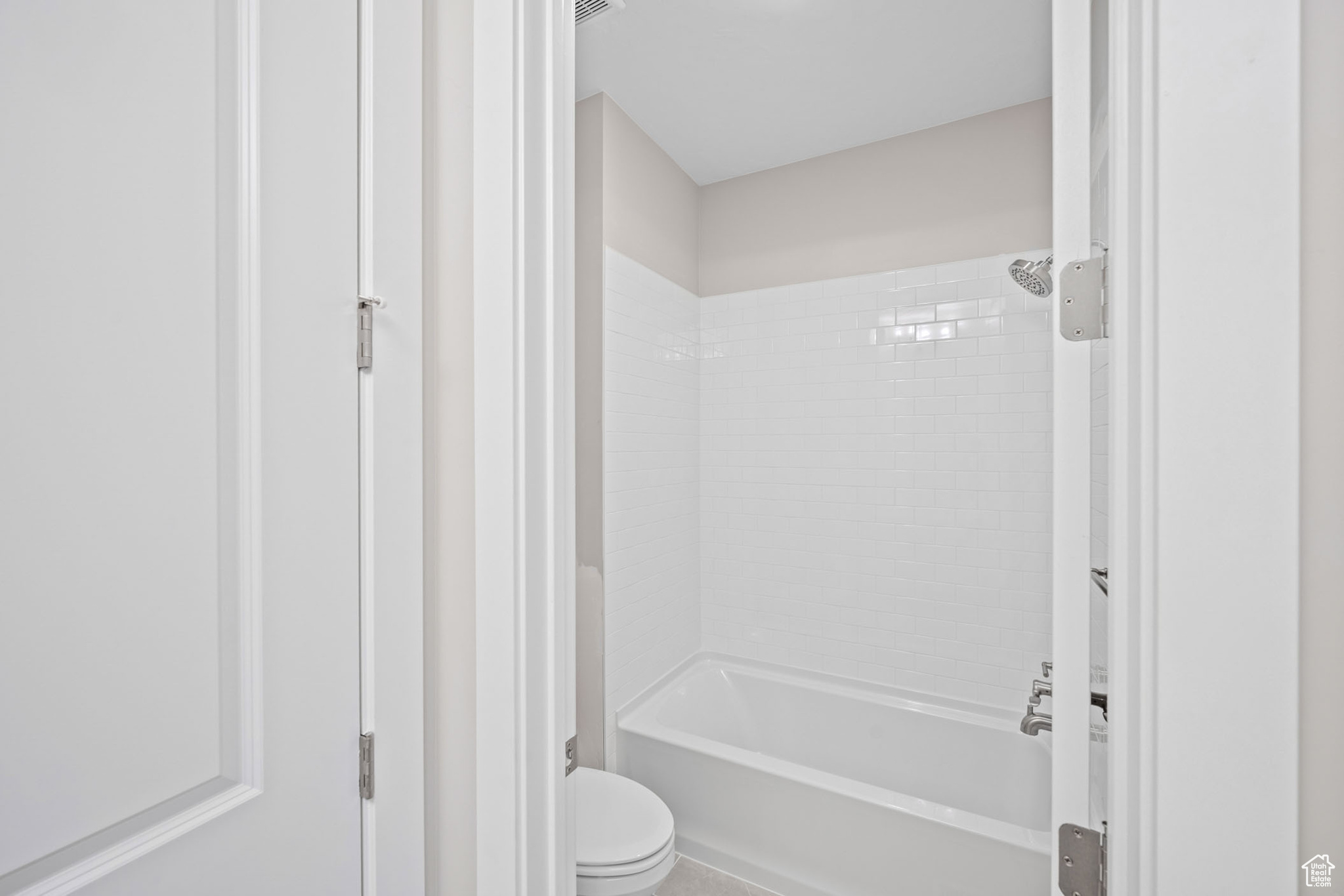 Bathroom featuring tiled shower / bath and toilet