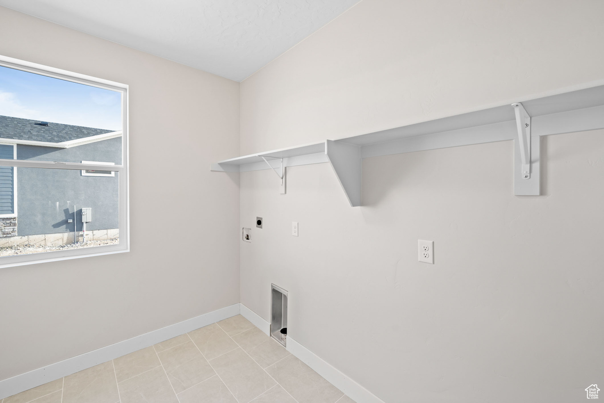 Washroom featuring electric dryer hookup and light tile patterned floors