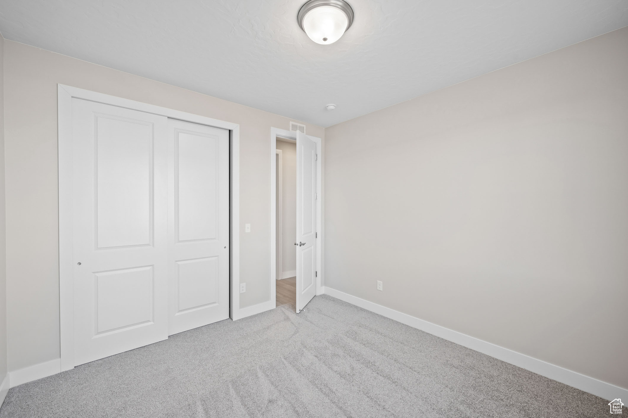 Unfurnished bedroom featuring light carpet and a closet