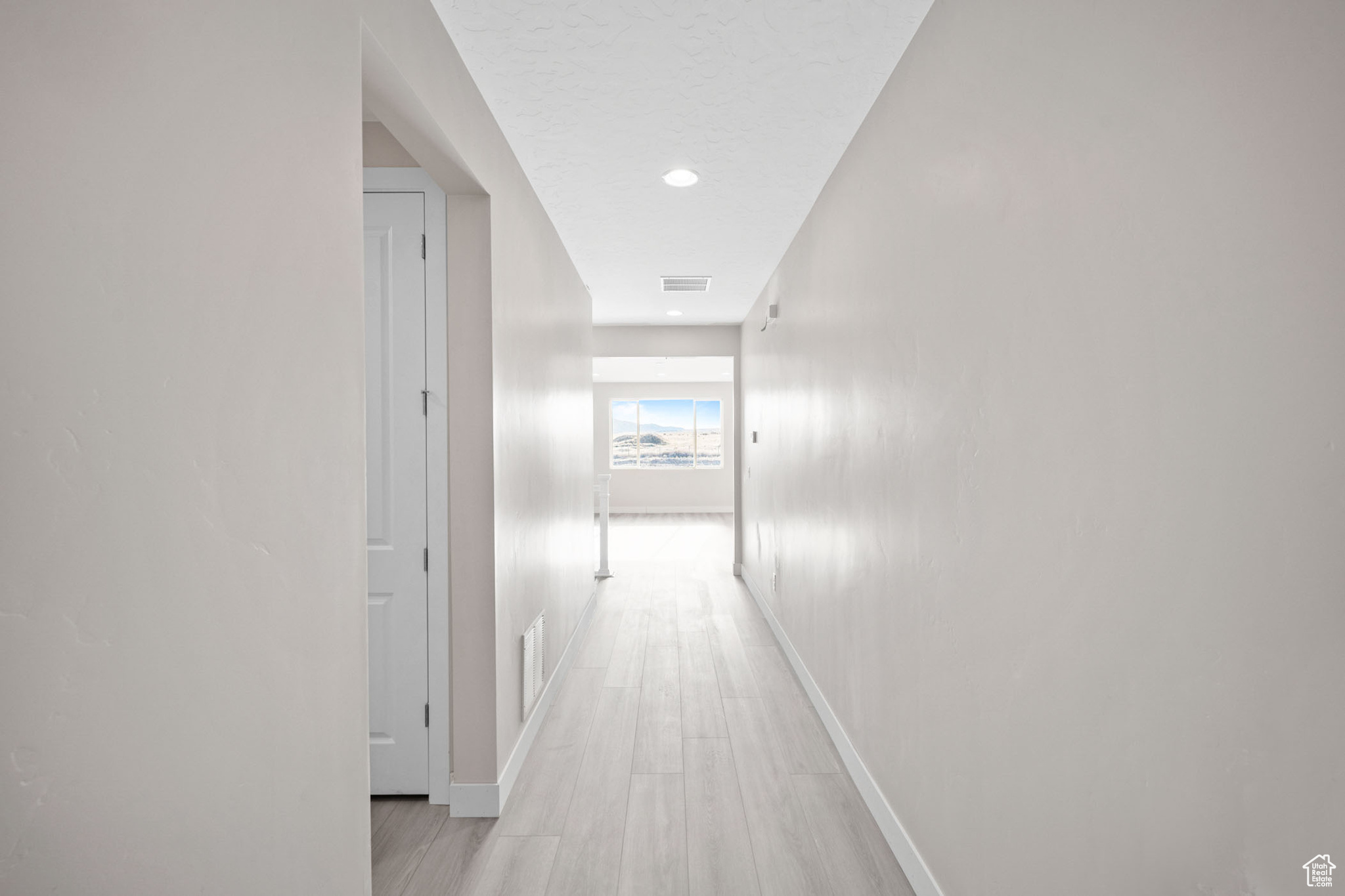 Hallway with a textured ceiling and light wood-type flooring