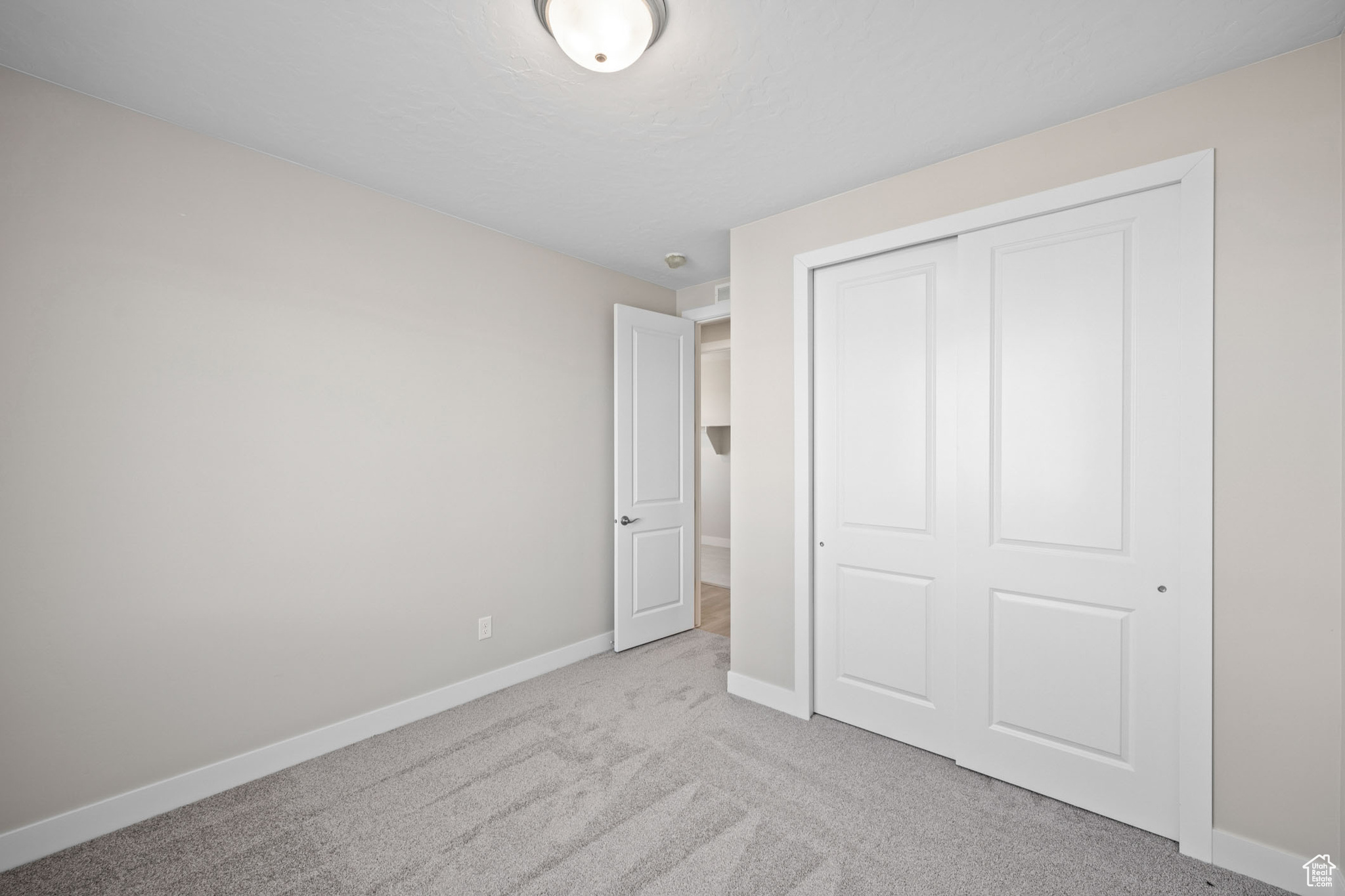 Unfurnished bedroom with light colored carpet and a closet