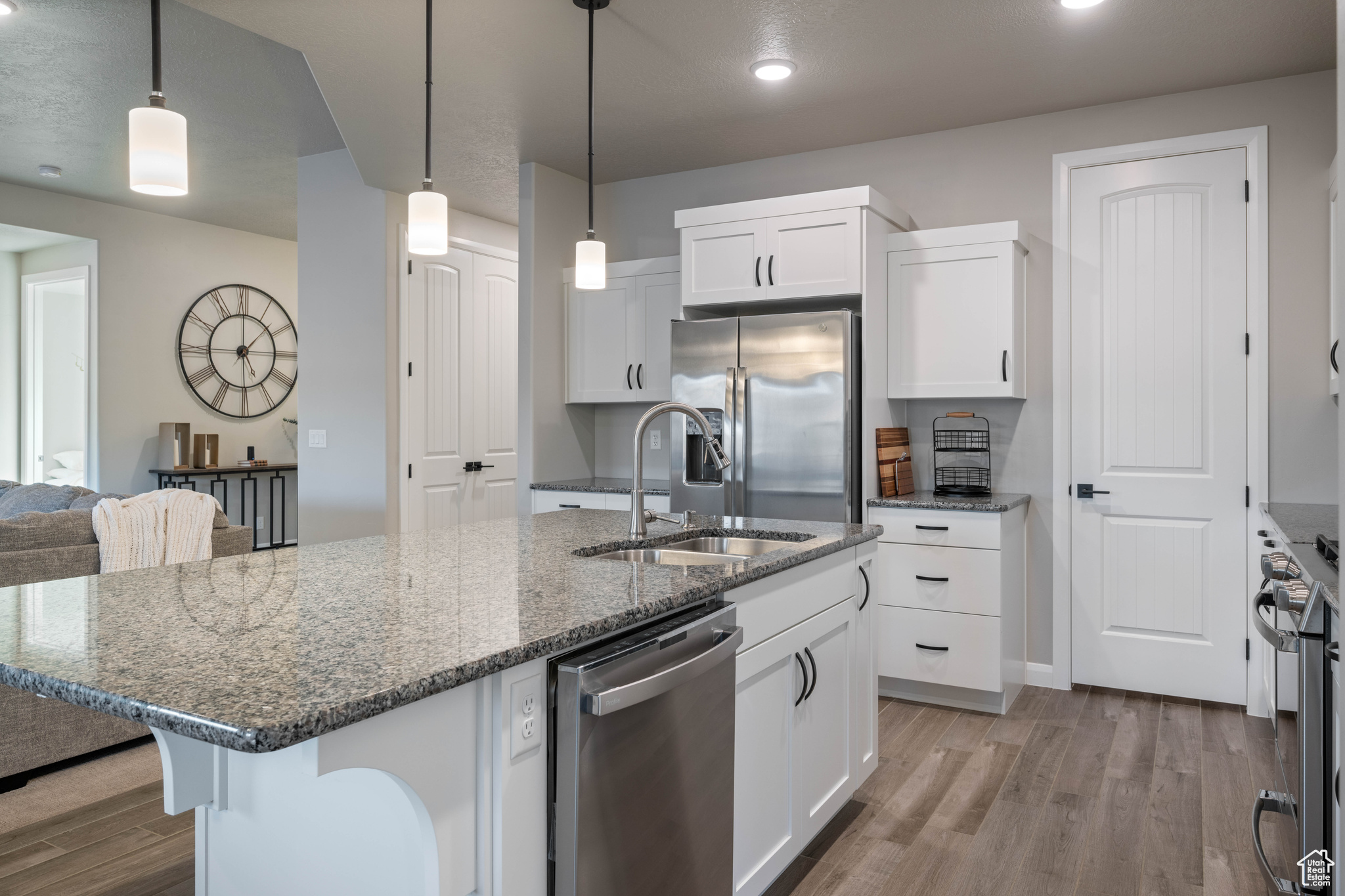 Kitchen featuring pendant lighting, sink, dark stone countertops, stainless steel appliances, and white cabinets