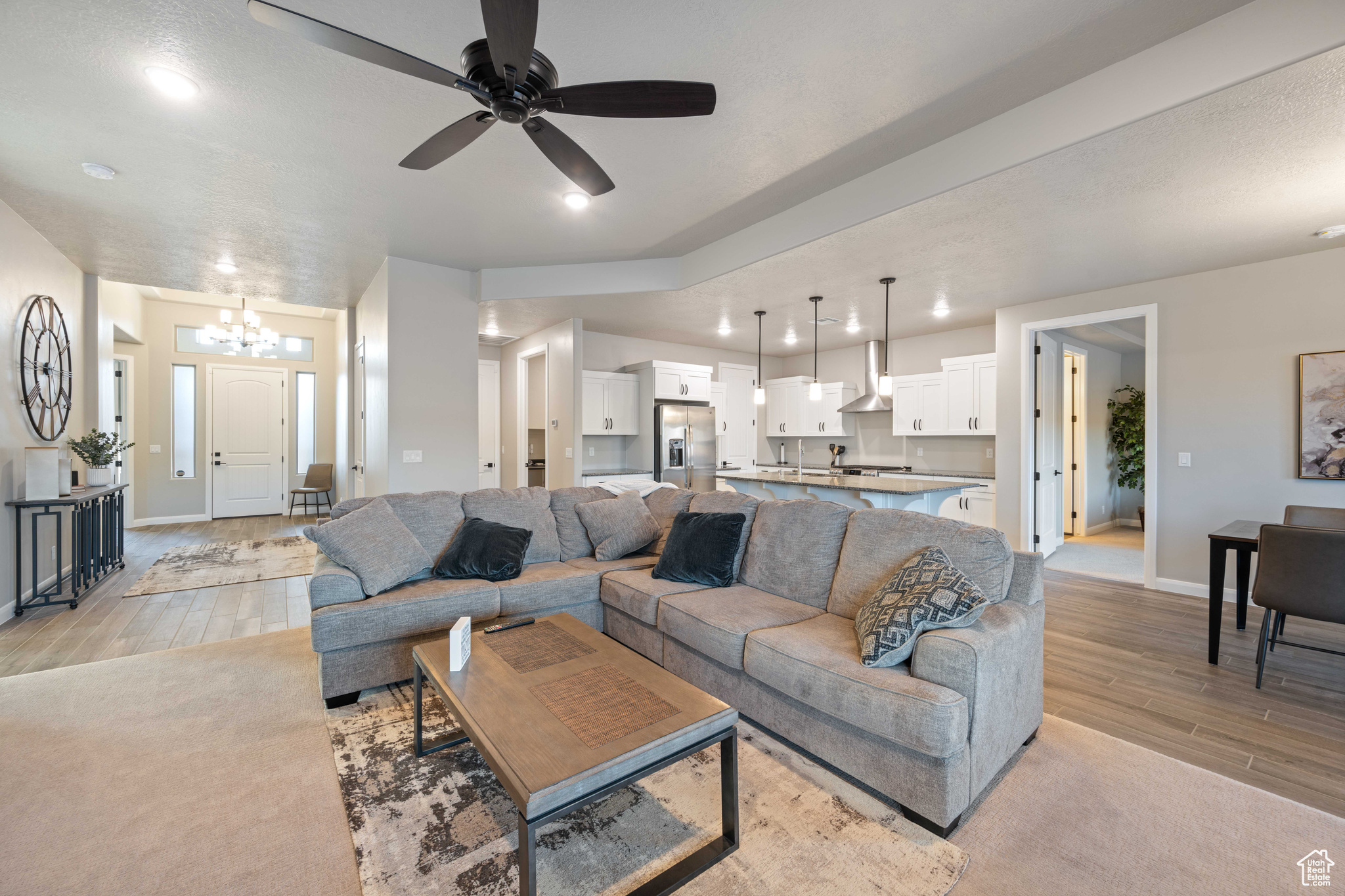 Living room featuring ceiling fan with notable chandelier and light wood-type flooring