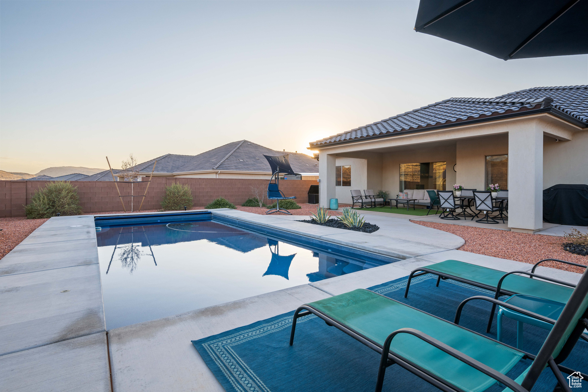 Pool at dusk featuring a patio and a grill