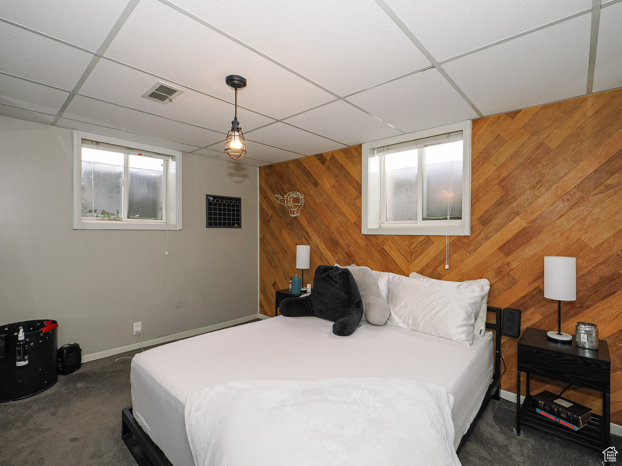 Carpeted bedroom featuring a drop ceiling and wood walls