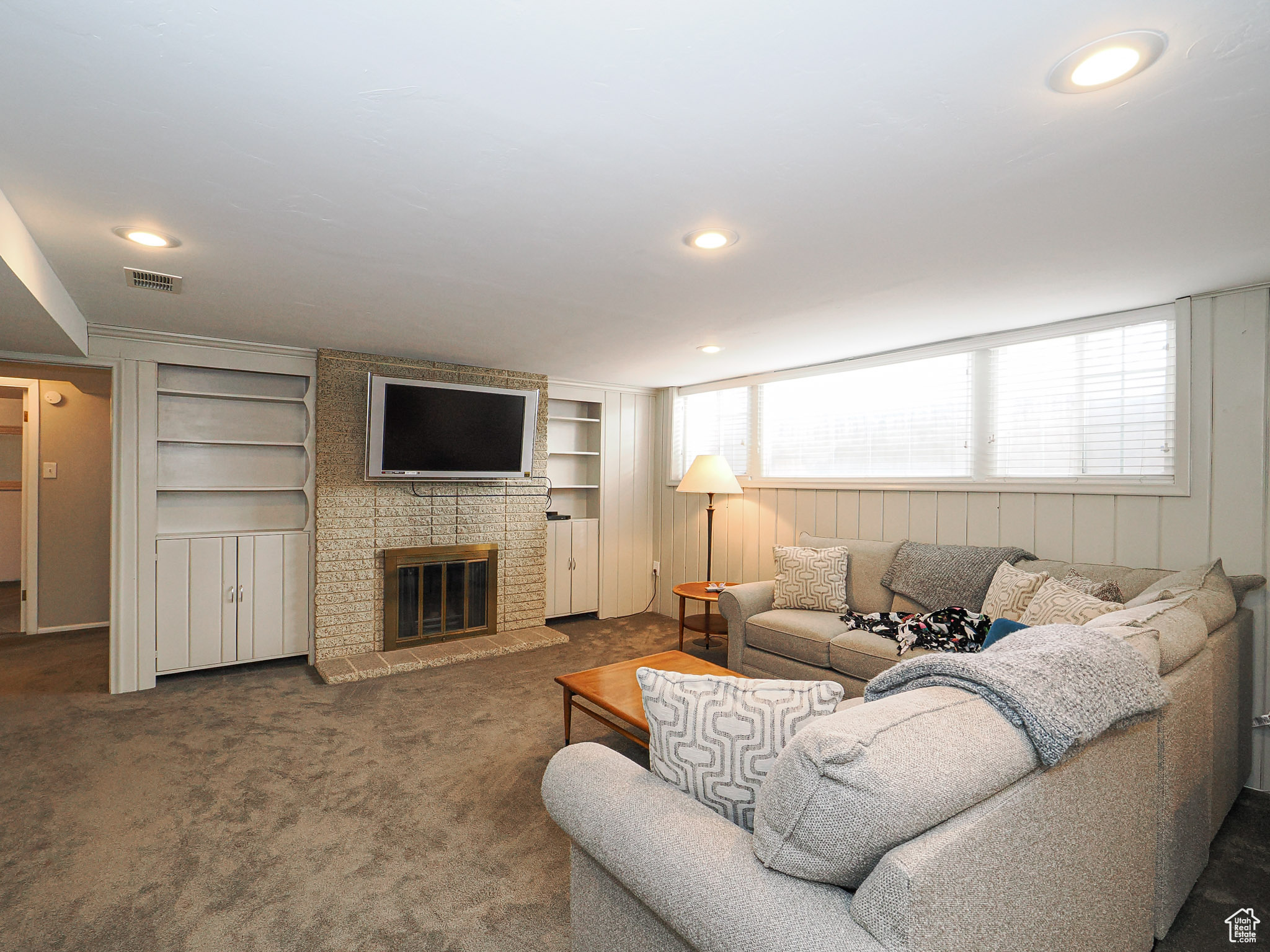 Living room featuring built in features, a fireplace, dark carpet, and wood walls