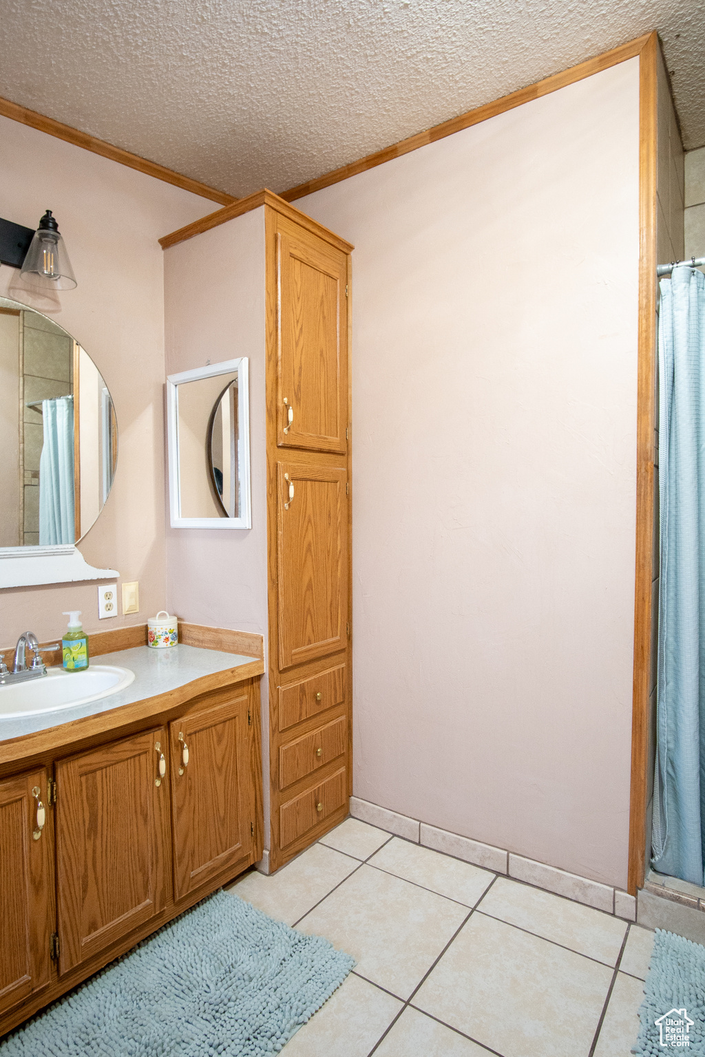 Bathroom featuring curtained shower, tile patterned flooring, vanity, crown molding, and a textured ceiling